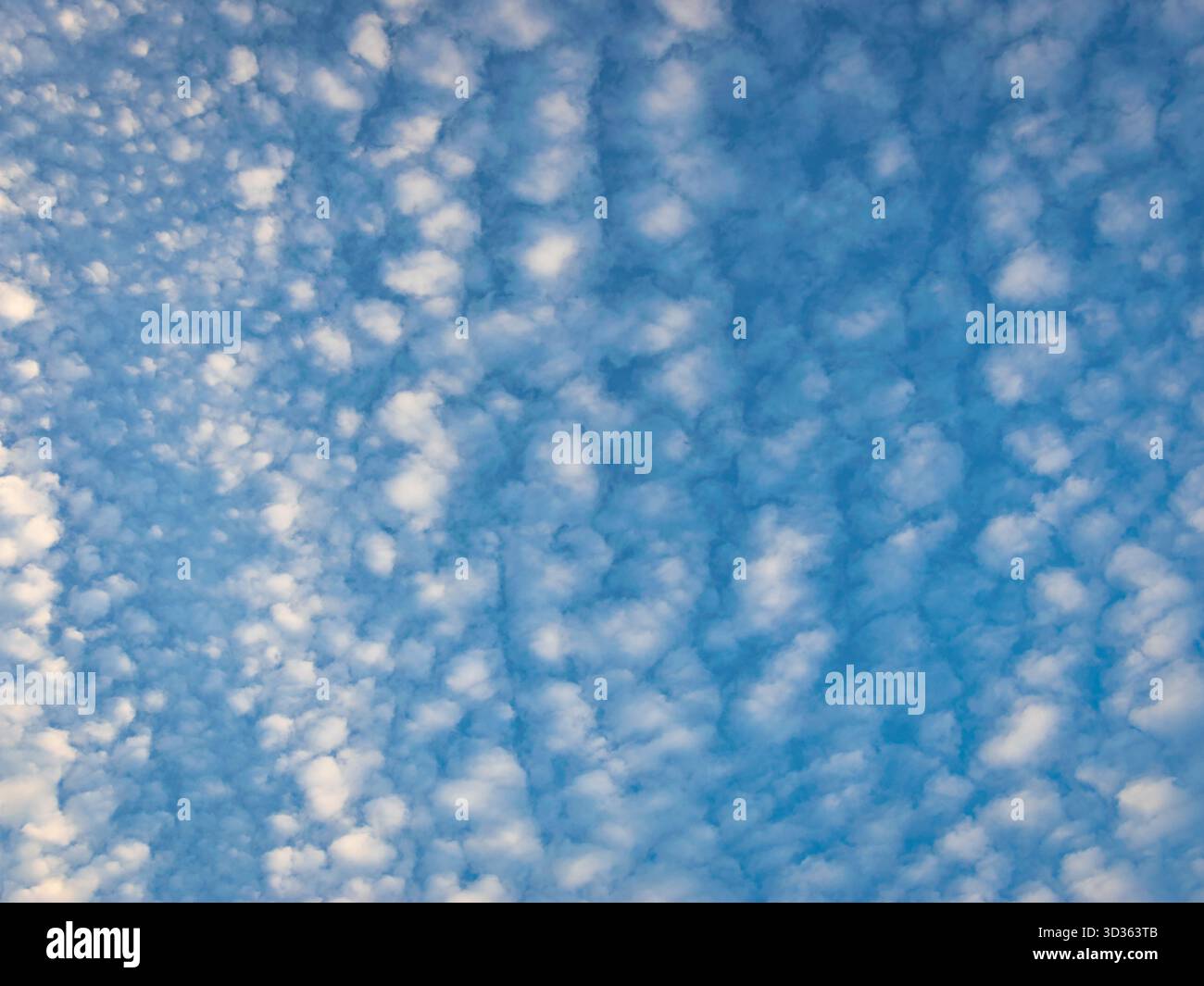 Clear blue sky with soft white clouds creating a peaceful and dreamy sky background Stock Photo