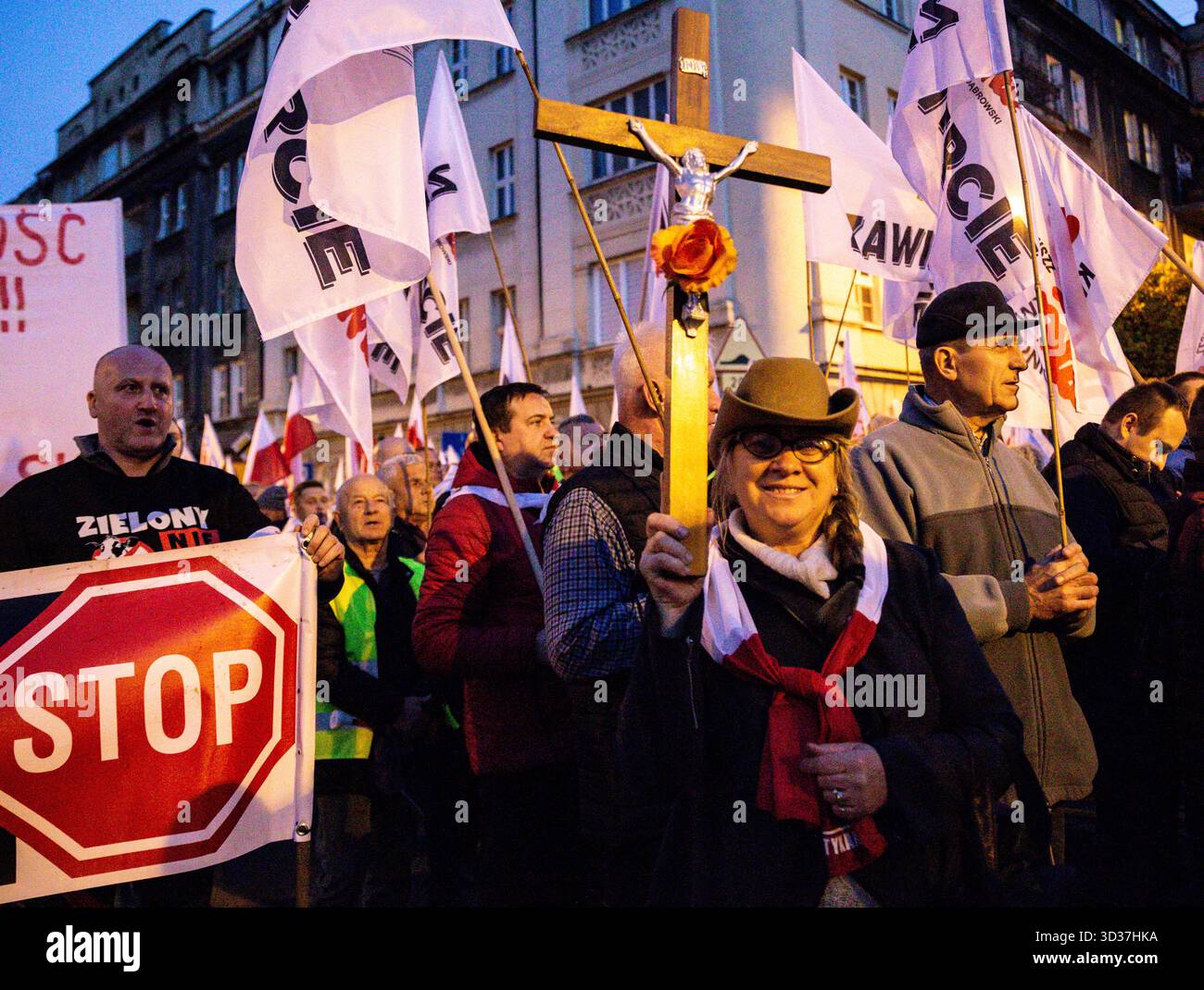 Katowice, Poland. 04th Nov, 2025. A woman holds a cross as coal miners and steelworks workers hold banners during a protest in front of Silesia voivodeship government office. Labour unions, primarily Solidarity movement, of mining and steel industries called for protest as negotiations with the Polish government on the issue of energy transformation did not bring satisfactory results. This week, the Polish government adopted a draft law which will protect miners leaving the industry, but the union say the law is not enough. Credit: SOPA Images Limited/Alamy Live News Stock Photo