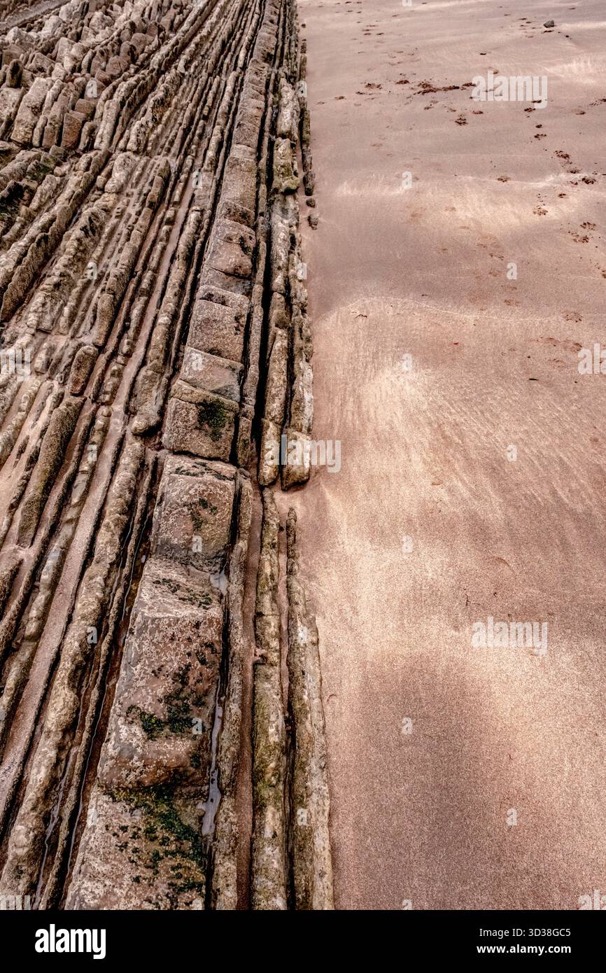 Geological Flysch Rock Formation Texture Running into the Beach Sand in Zumaia, Basque Country, Spain Stock Photo