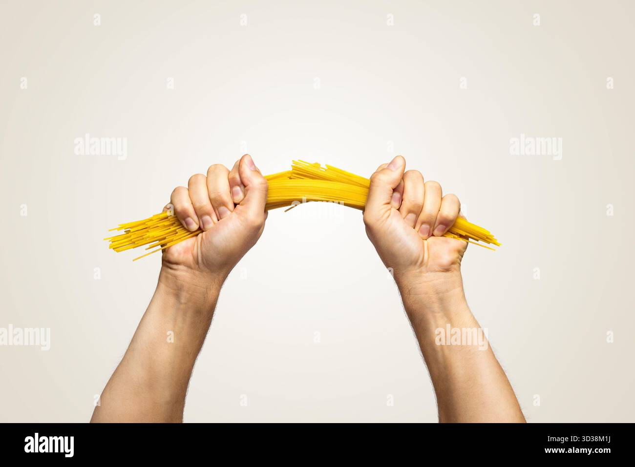 Two hands breaking spaghetti pasta in half Stock Photo
