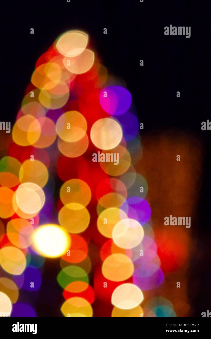 winter holiday colorful bokeh. festive decorated christmas tree lights on city street for beautiful new year abstract background. defocused red and ye Stock Photo
