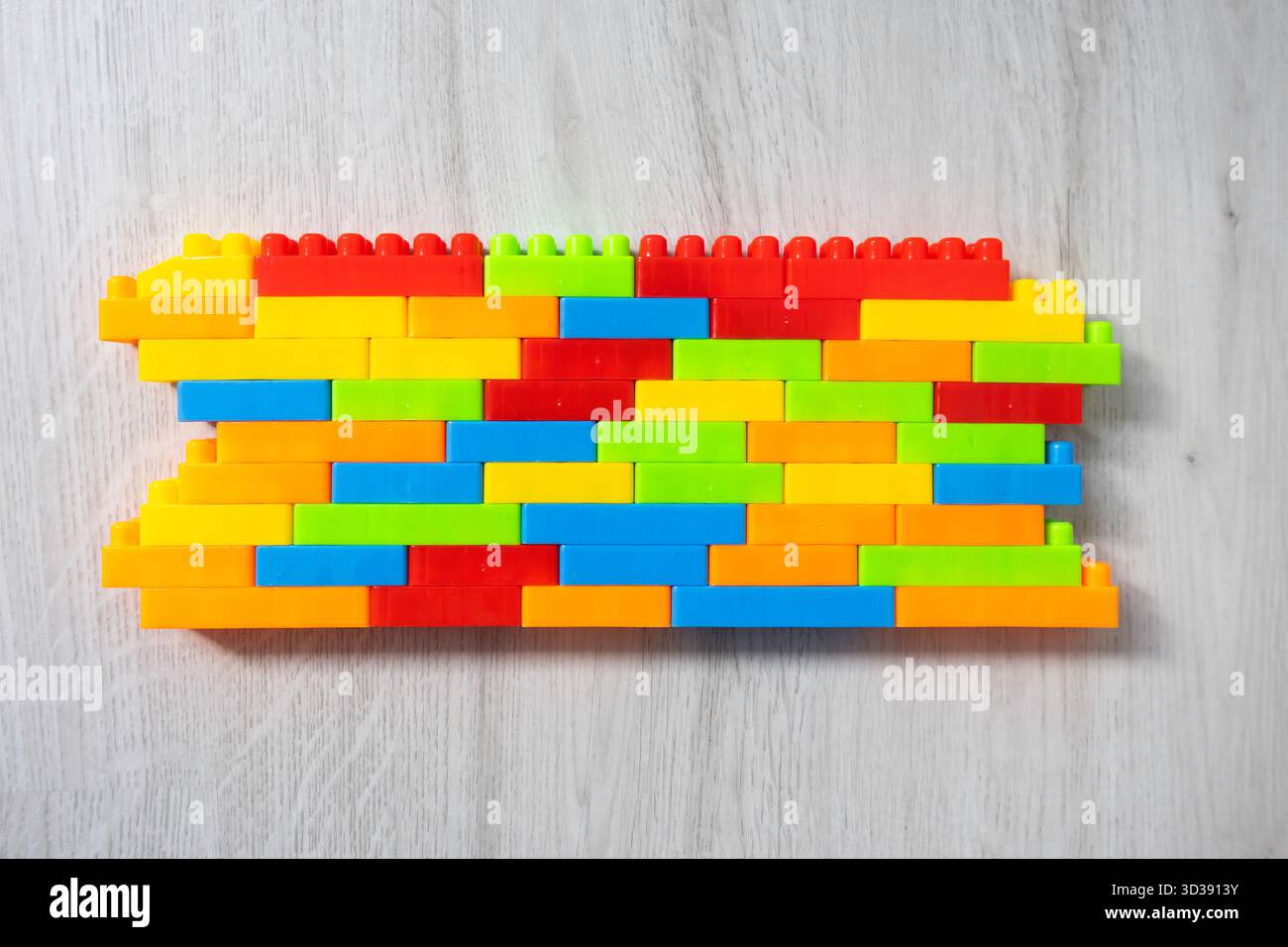 Assembled multi-colored plastic construction blocks lie on the floor. Stock Photo