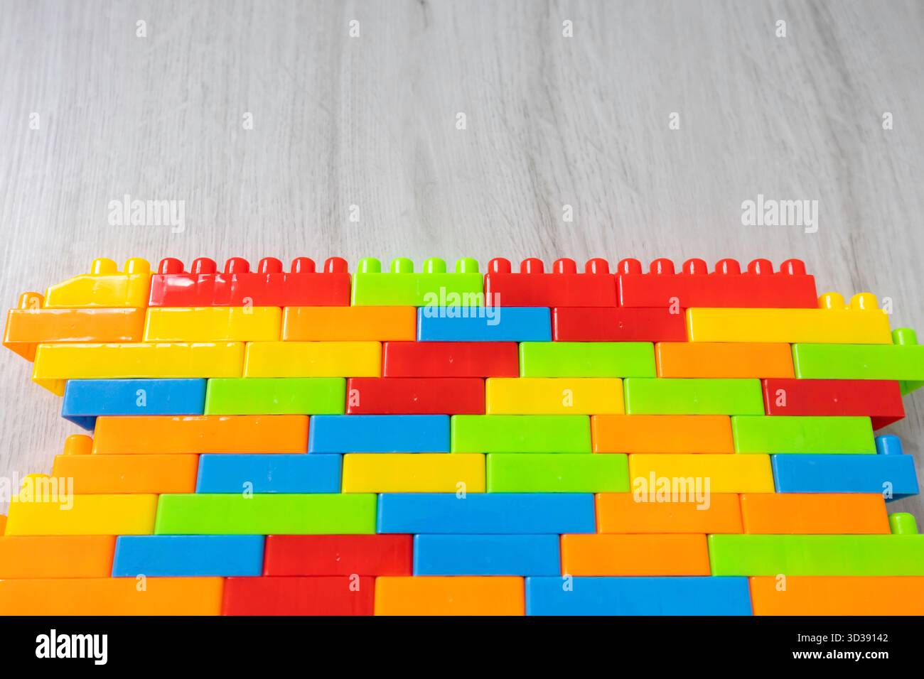 Assembled multi-colored plastic construction blocks lie on the floor. Stock Photo