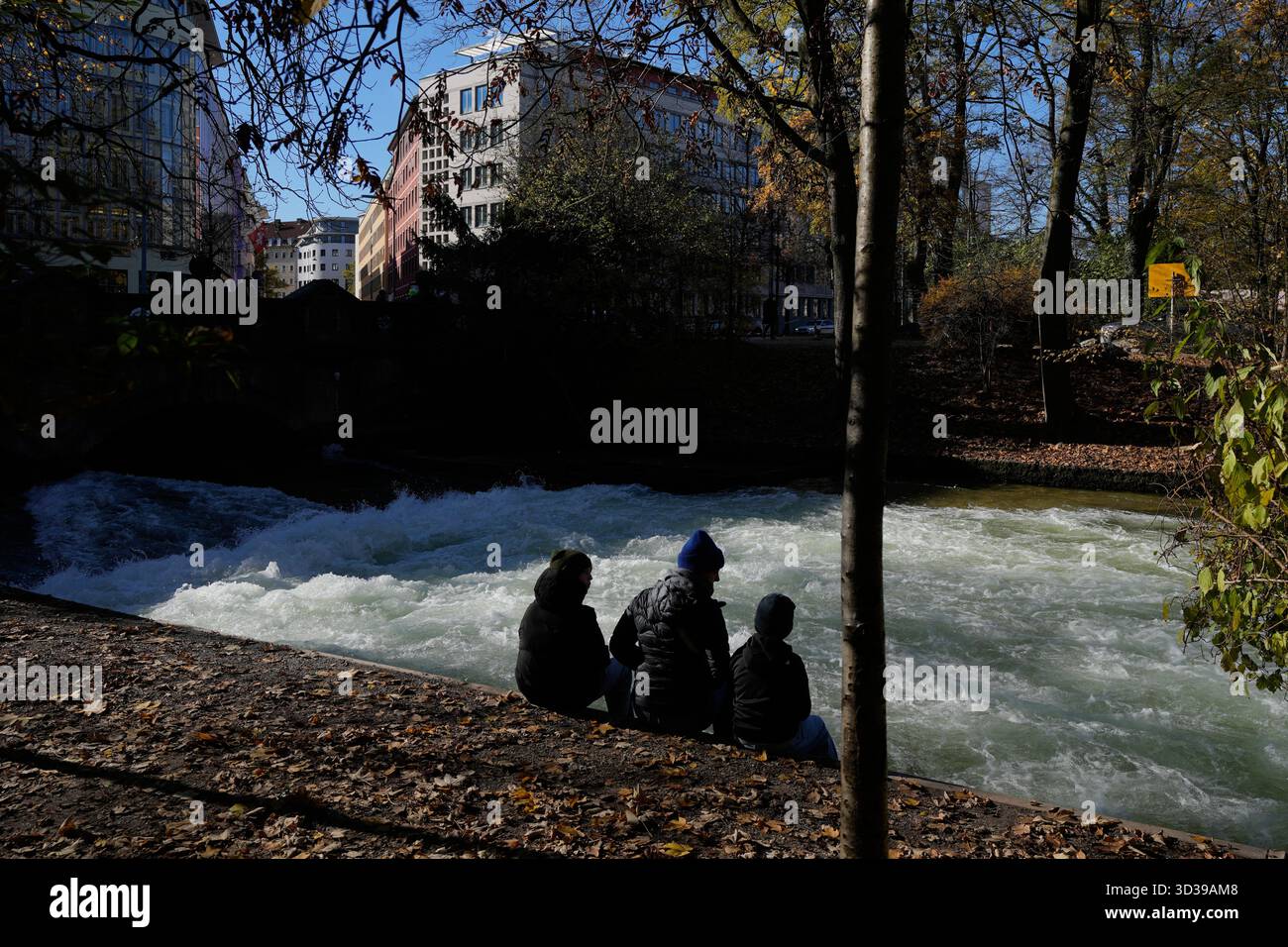 People sit at the Eisbach, where the famous wave usually forms, in ...