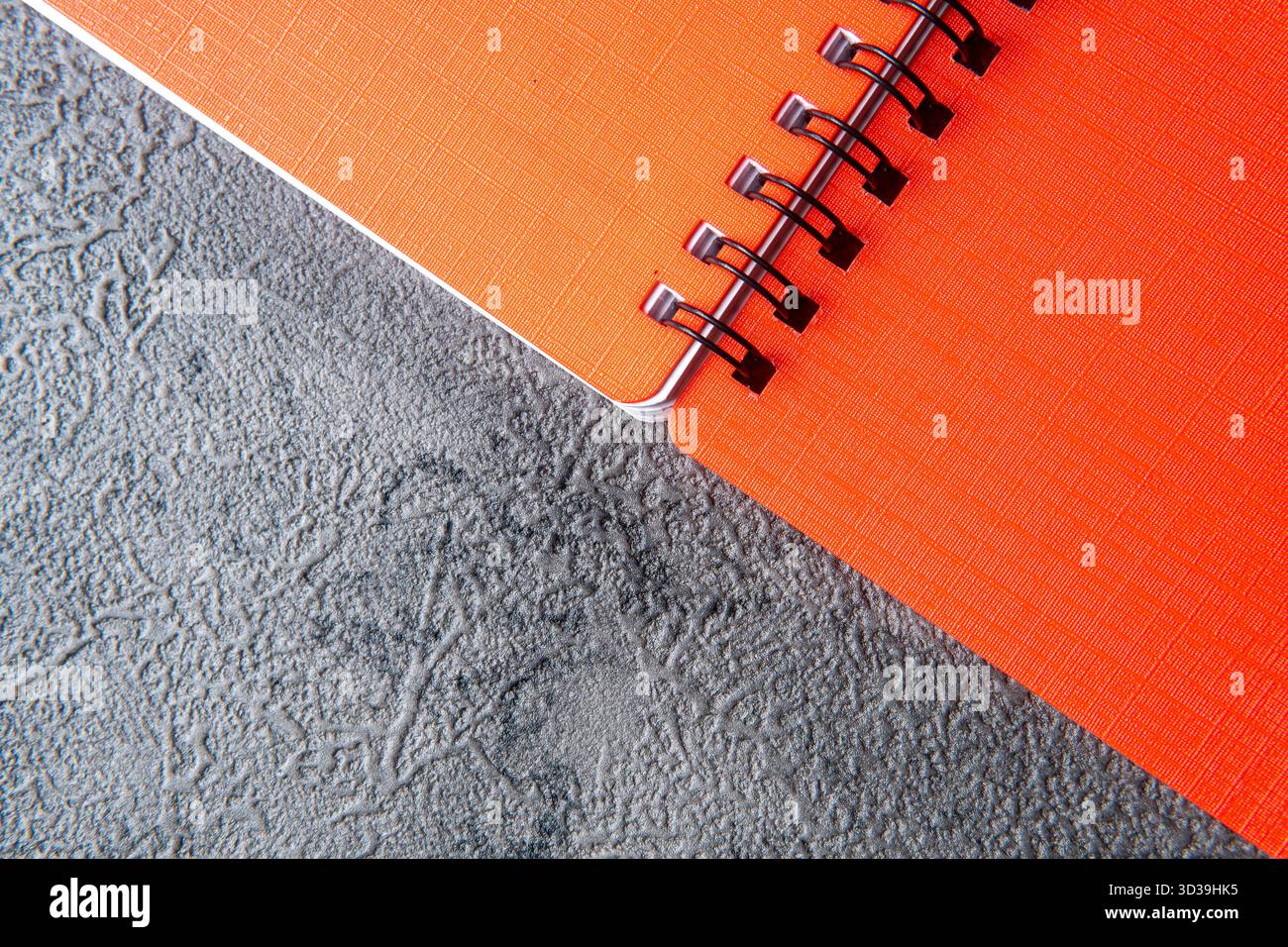 Orange Spiral Notebook on a Dark Gray Textured Background Stock Photo