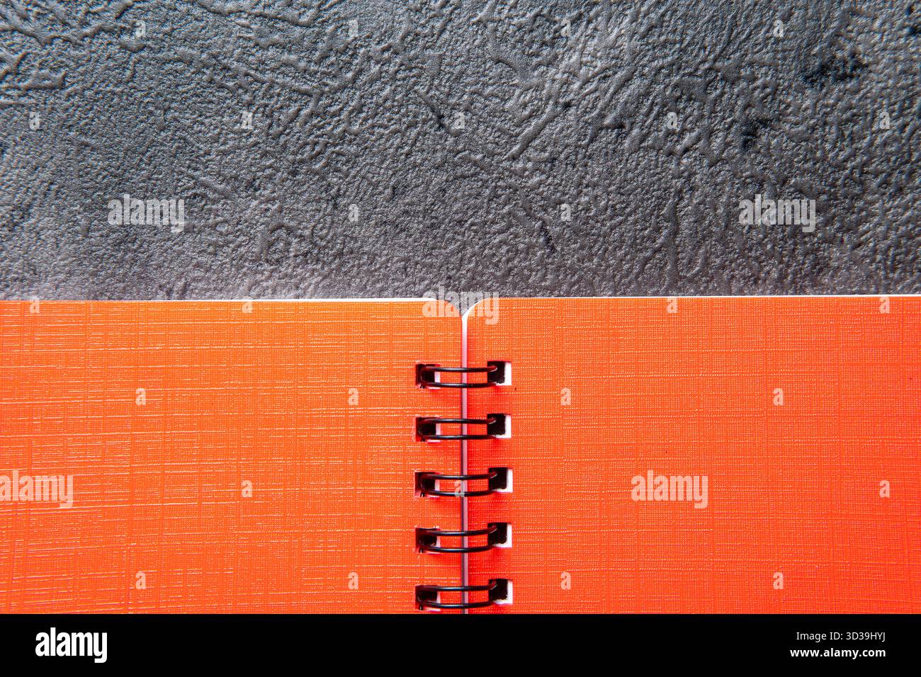 Orange Spiral Notebook on a Dark Gray Textured Background Stock Photo