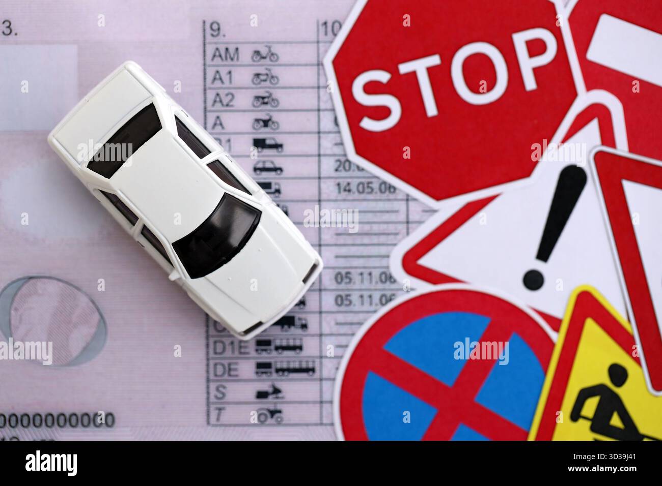 Driving school concept. Toy car and road signs on driver license close ...