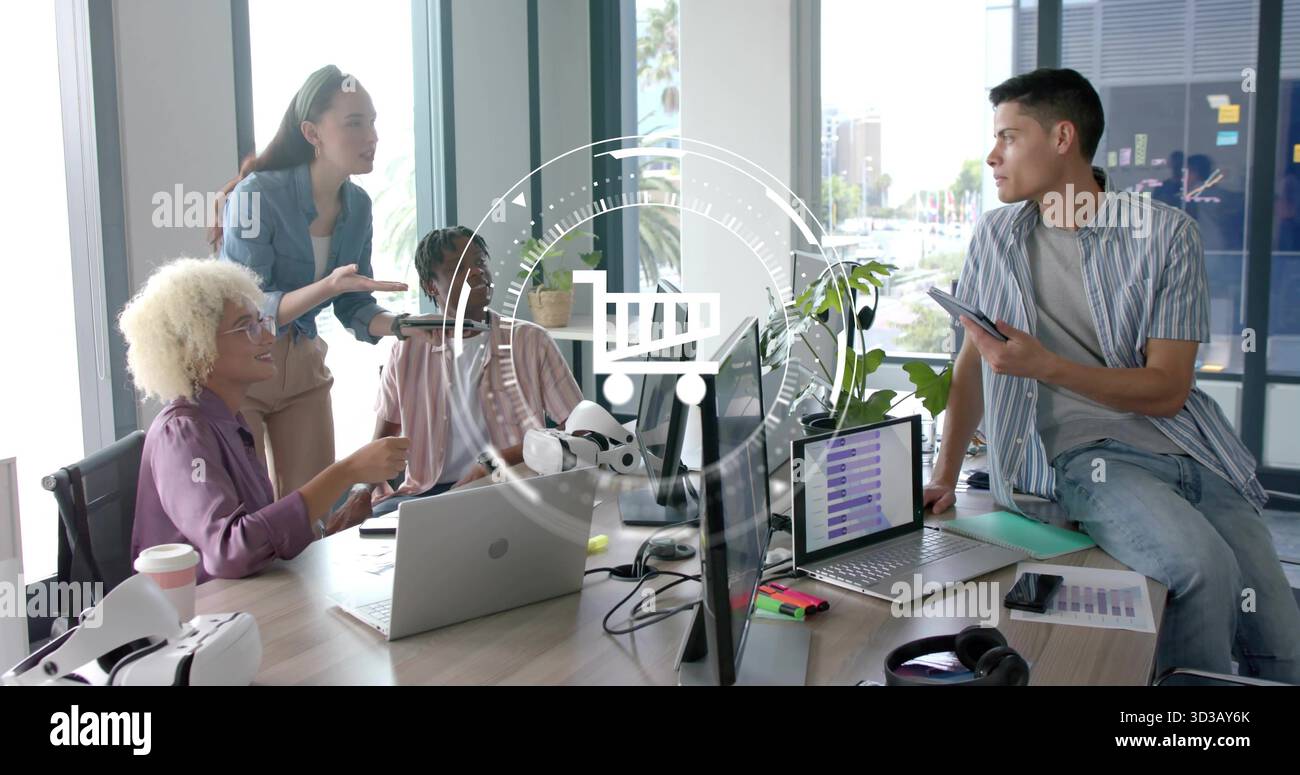 Collaborating colleagues discussing tech presentation at office table, with laptops and VR headset Stock Photo
