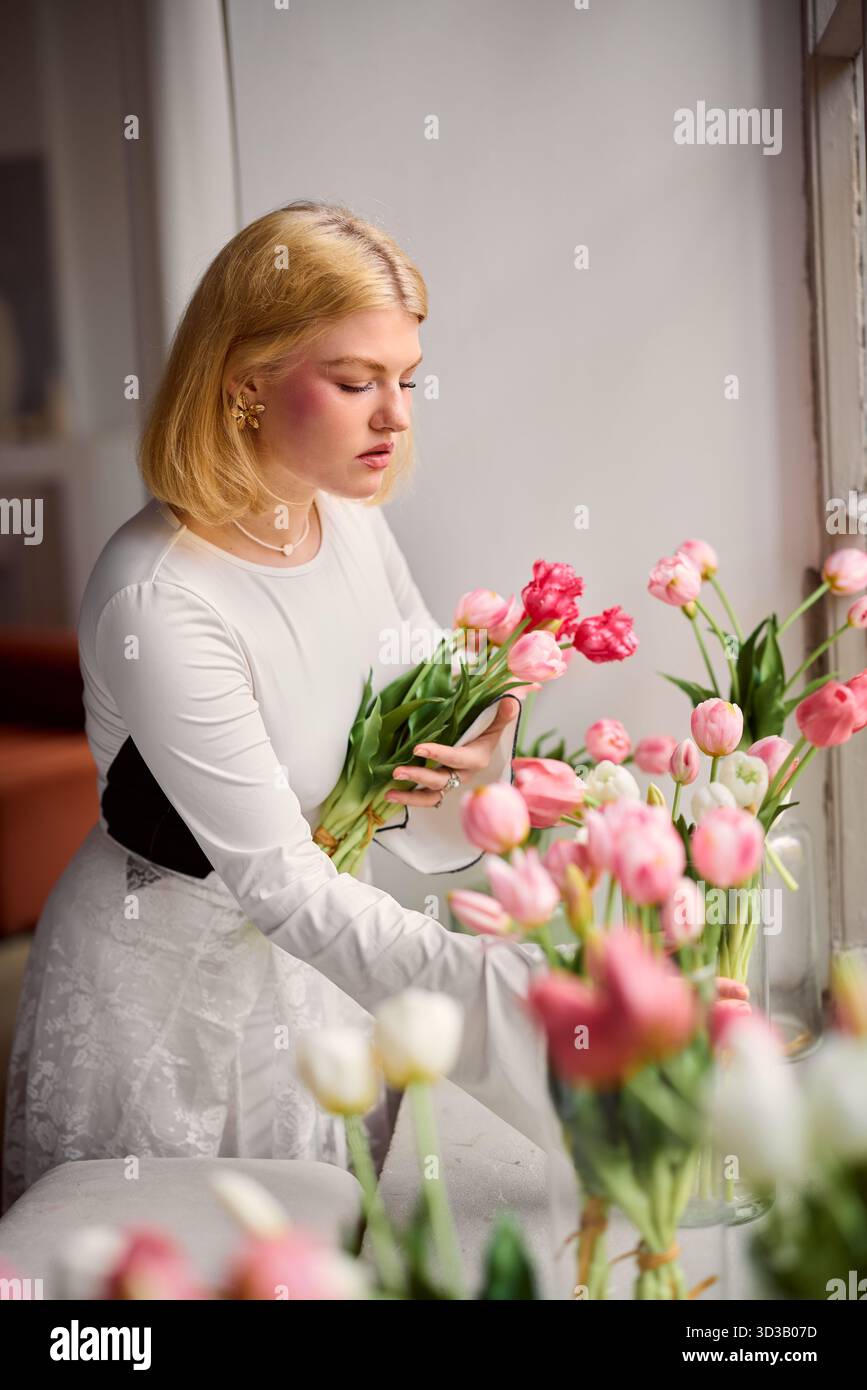Reflective artist methodically prepares flowers in gentle Stock Photo