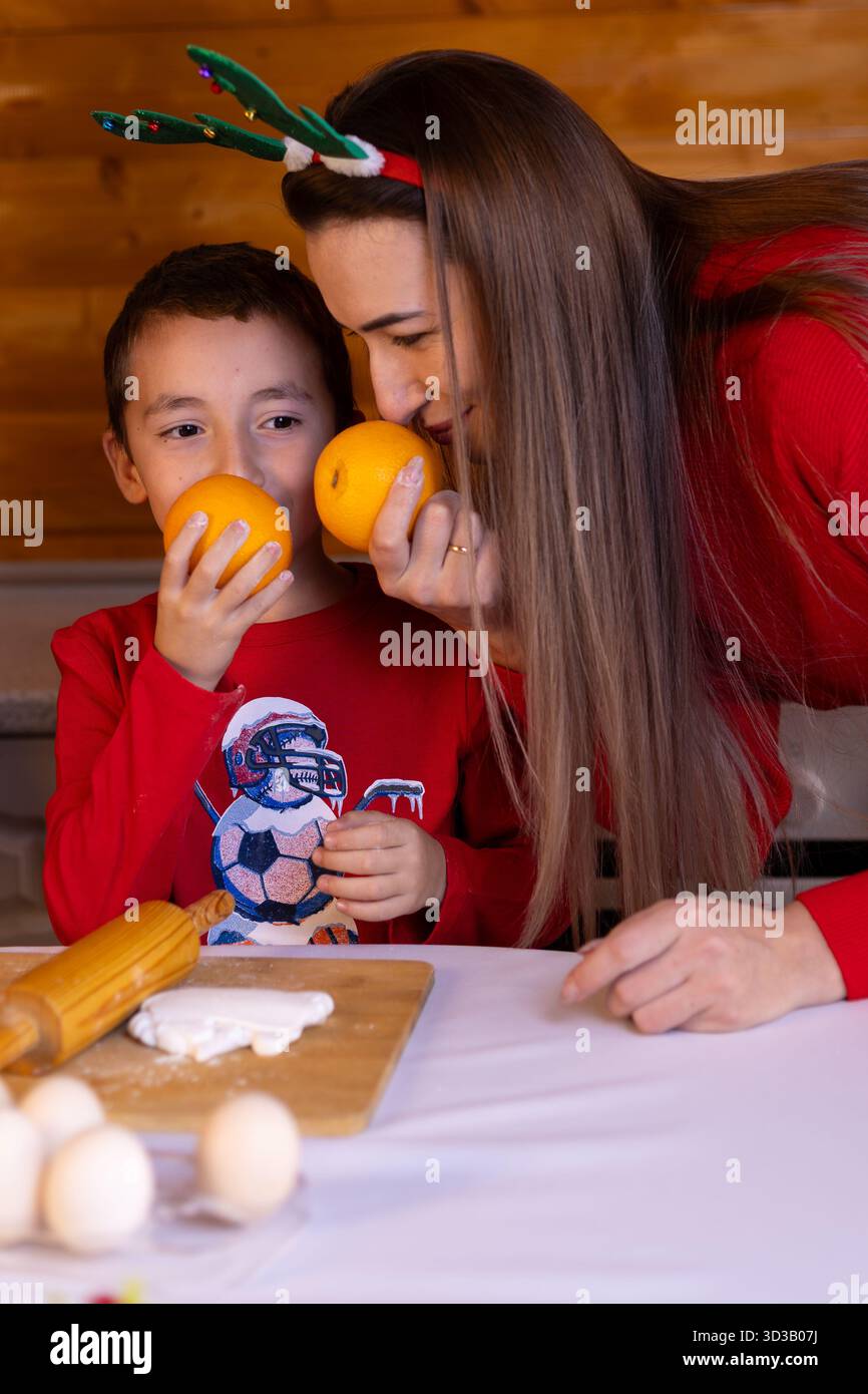 A mother and her child are smelling oranges, a festive Christmas tradition Stock Photo