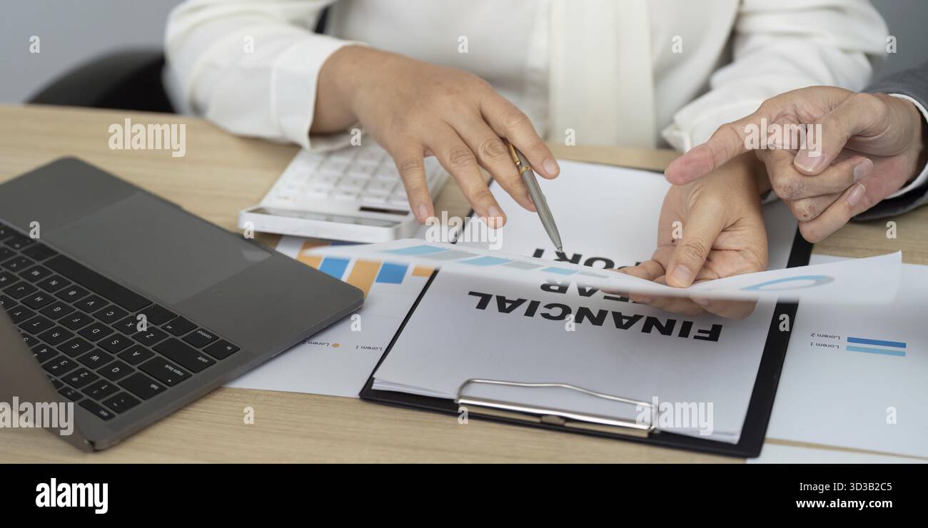 Business partners analyzing financial documents and graphs, focusing on strategic planning and fiscal responsibility Stock Photo