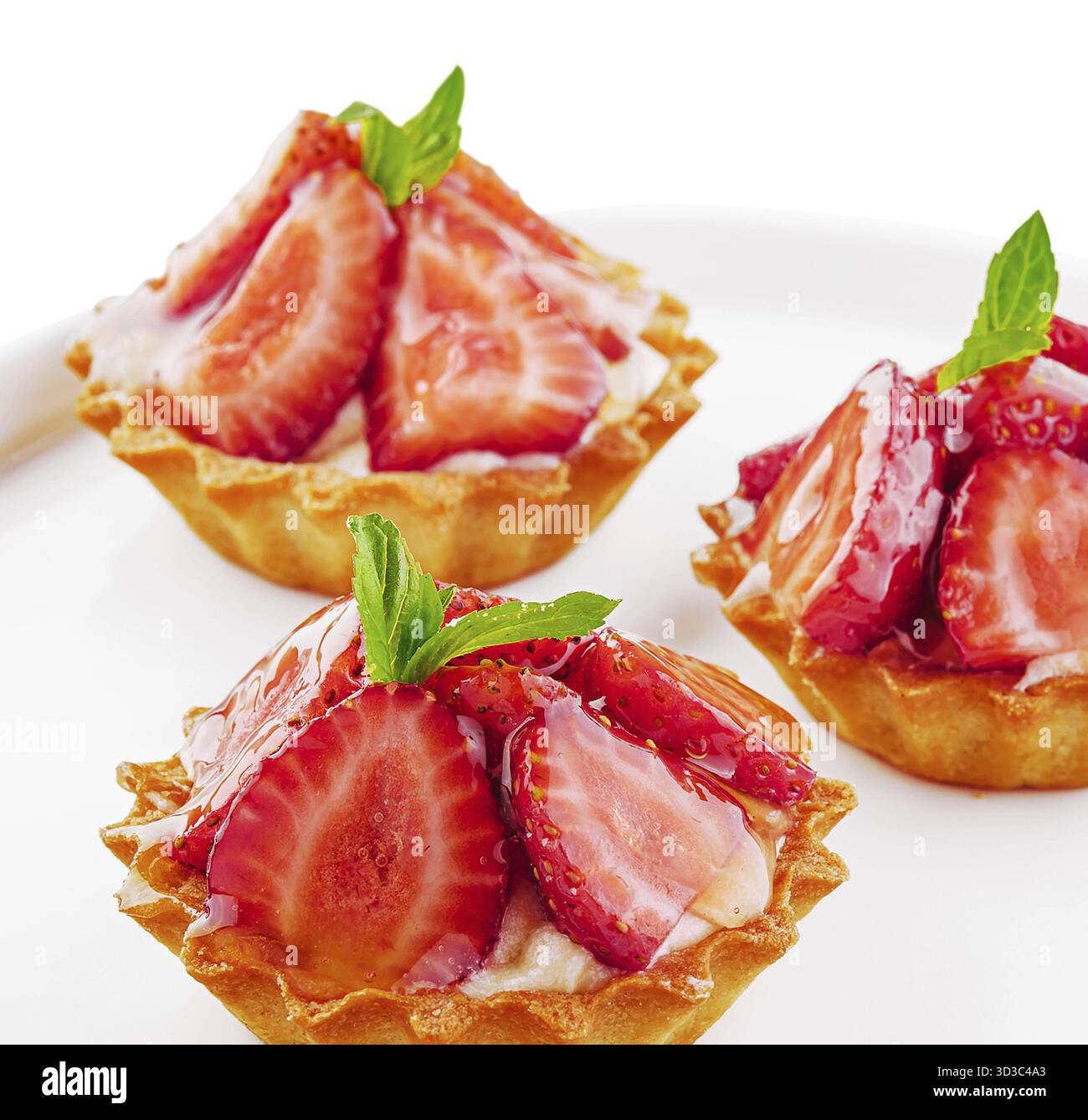 Food, Tartlets with custard, strawberries and mint served on white plate Stock Photo
