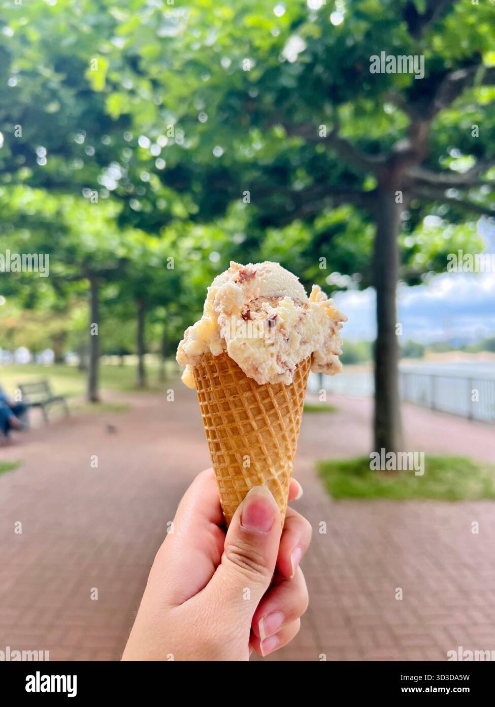 Hand holding an ice cream cone outdoors - Smartphone Captured Stock Image