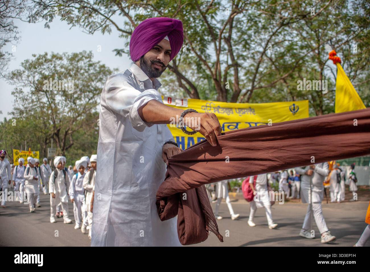 A Sikh man prepares cloth for making turbans as part of a seva ...