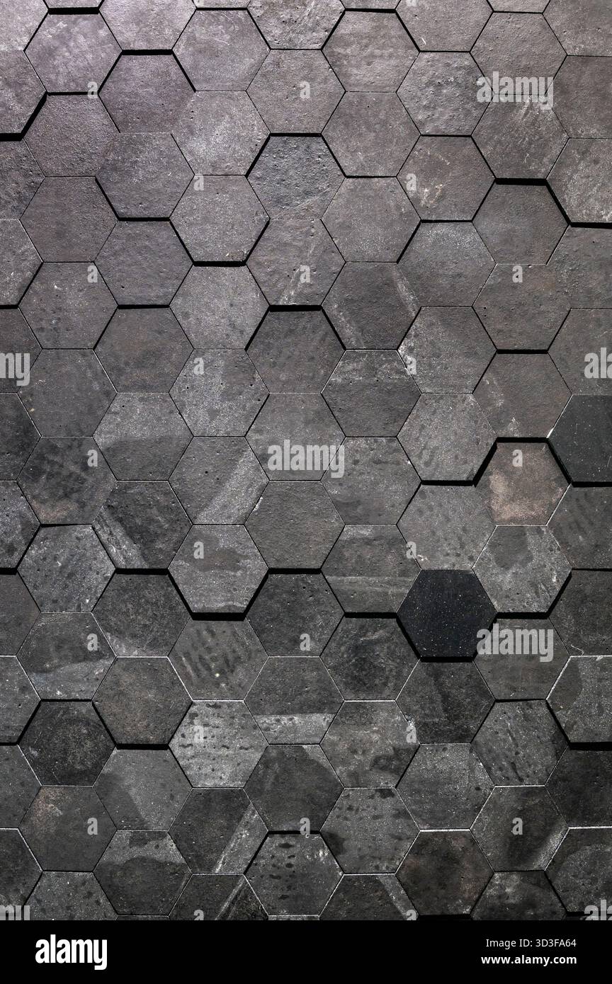 Dark gray hexagonal tiles forming a geometric textured wall surface Stock Photo