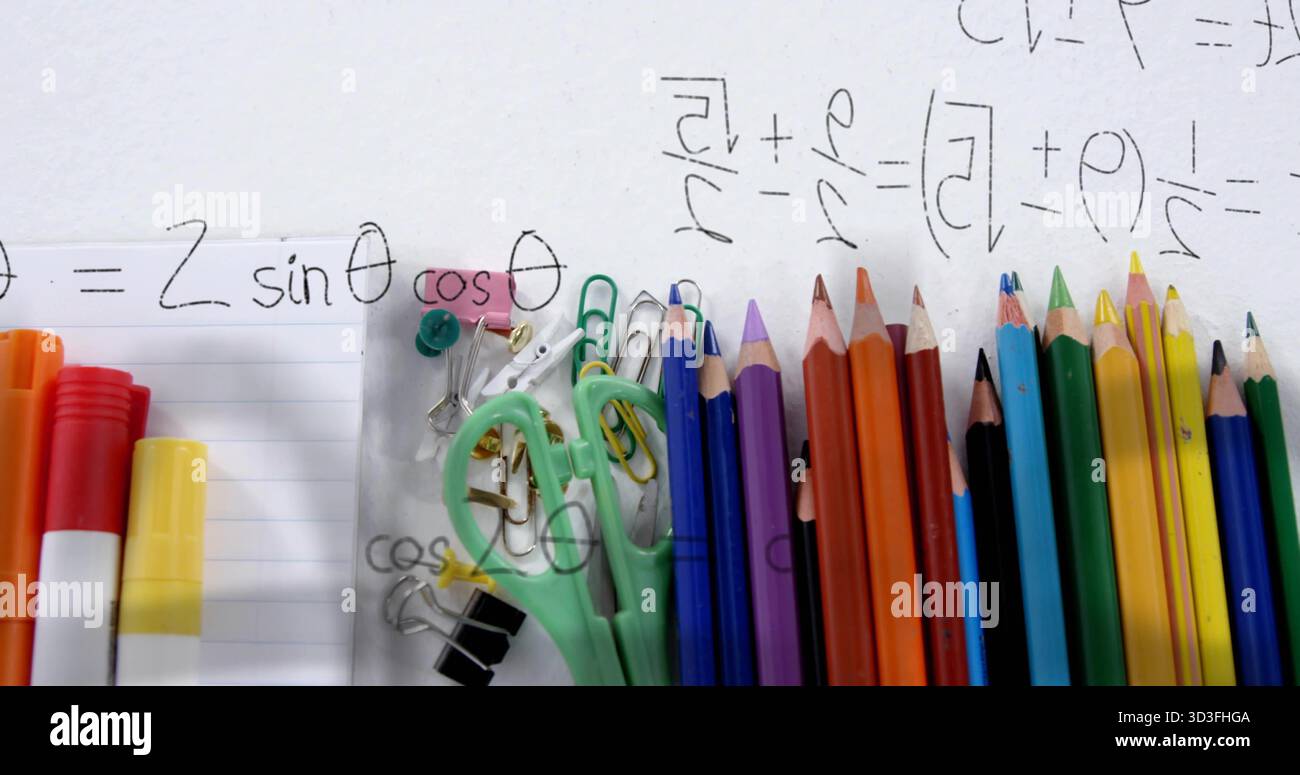 Displaying stationery on study desk with colored pencils, scissors, clips, pins and math scribbles Stock Photo