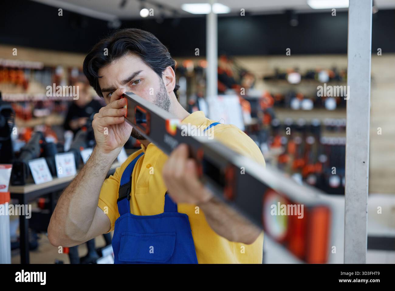 A man worker taking measurements using a bubble level tool inside a store Stock Photo