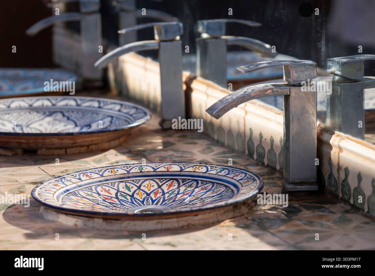 Row of the Moroccan ceramic wash basin in public toilet. Close up of the Moroccoan traditional bathroom sink in restroom in restaurant or hotel. Stock Photo
