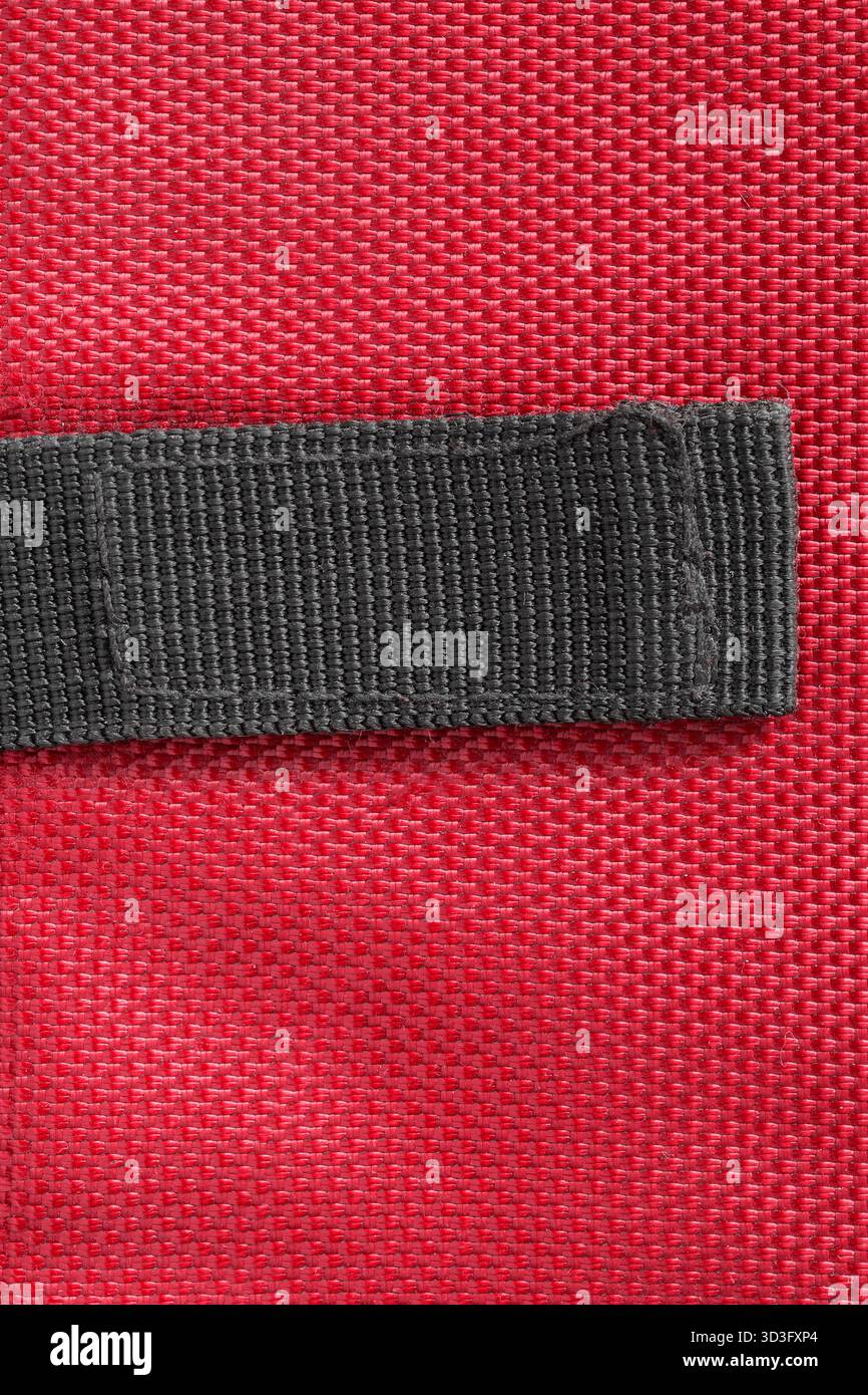 Black blank patch stitched on red waterproof fabric background Stock Photo