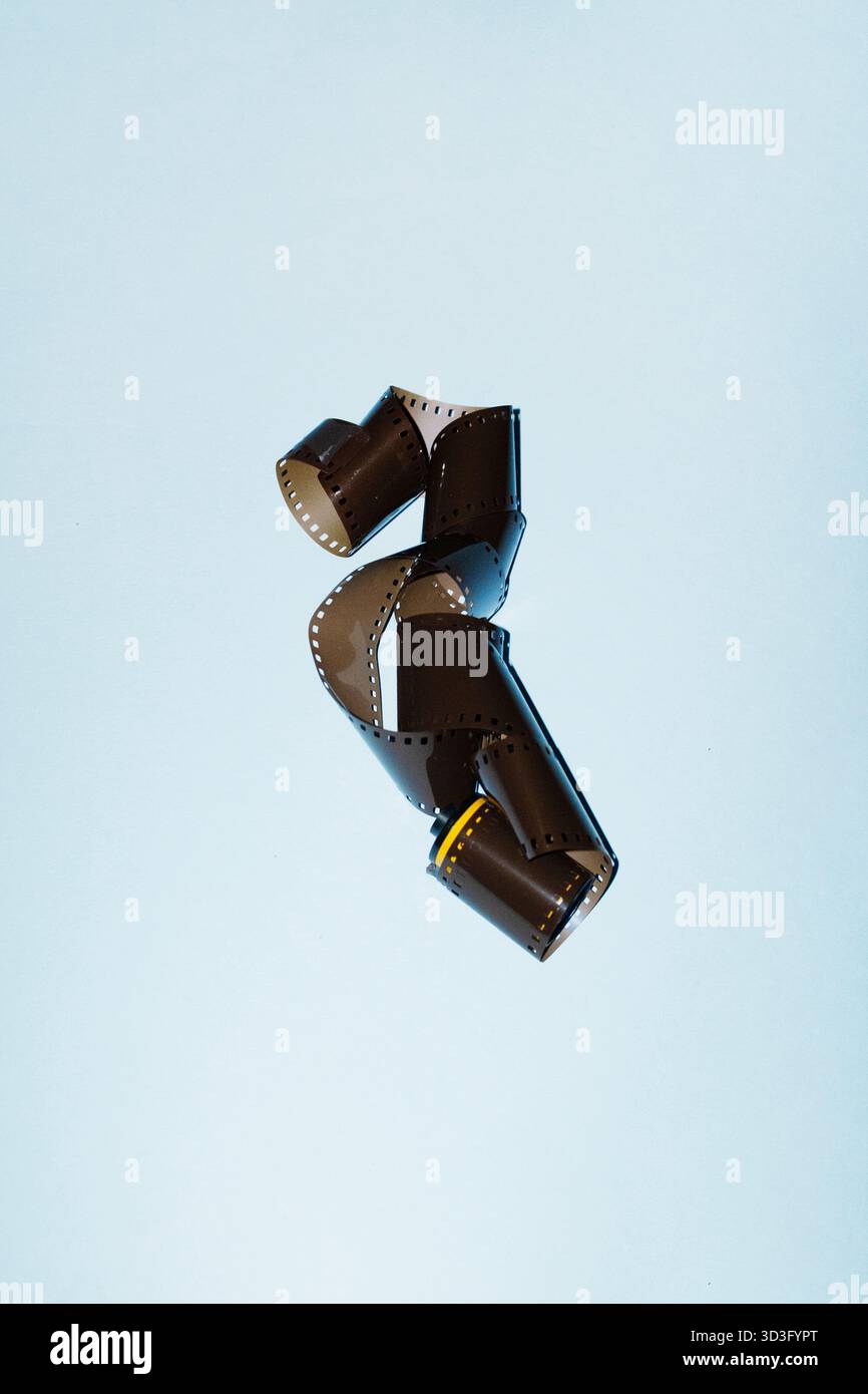 An intriguing still life image features a curled film roll against a light background. The scene highlights the texture and simplicity of traditional Stock Photo