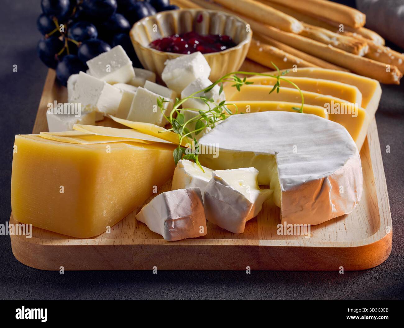 cheese plate and bread sticks on dark grey table background Stock Photo