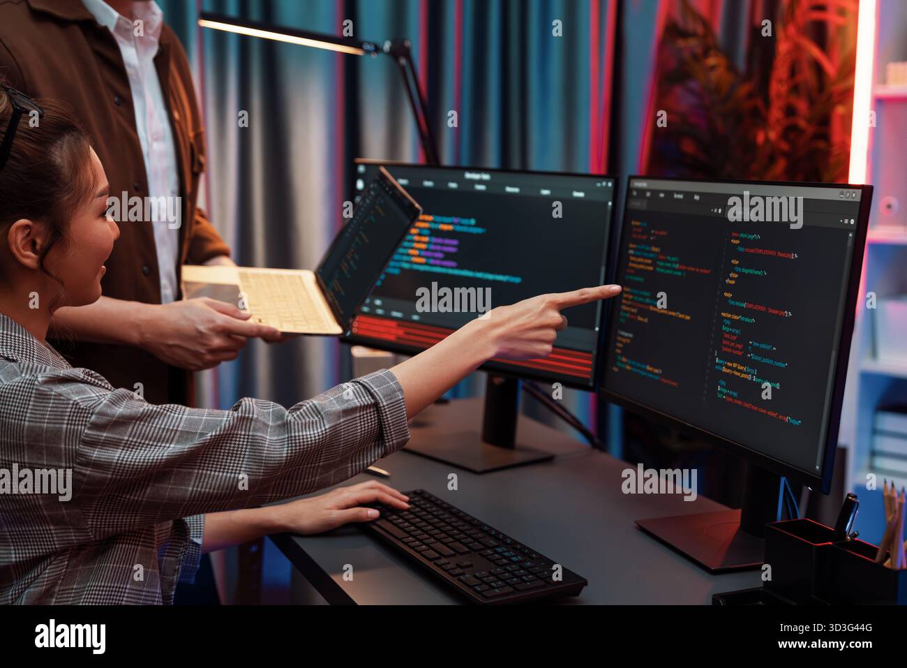 Serious of IT developers discussing intelligent website development coder system running data online two screens with laptop showing information Stock Photo