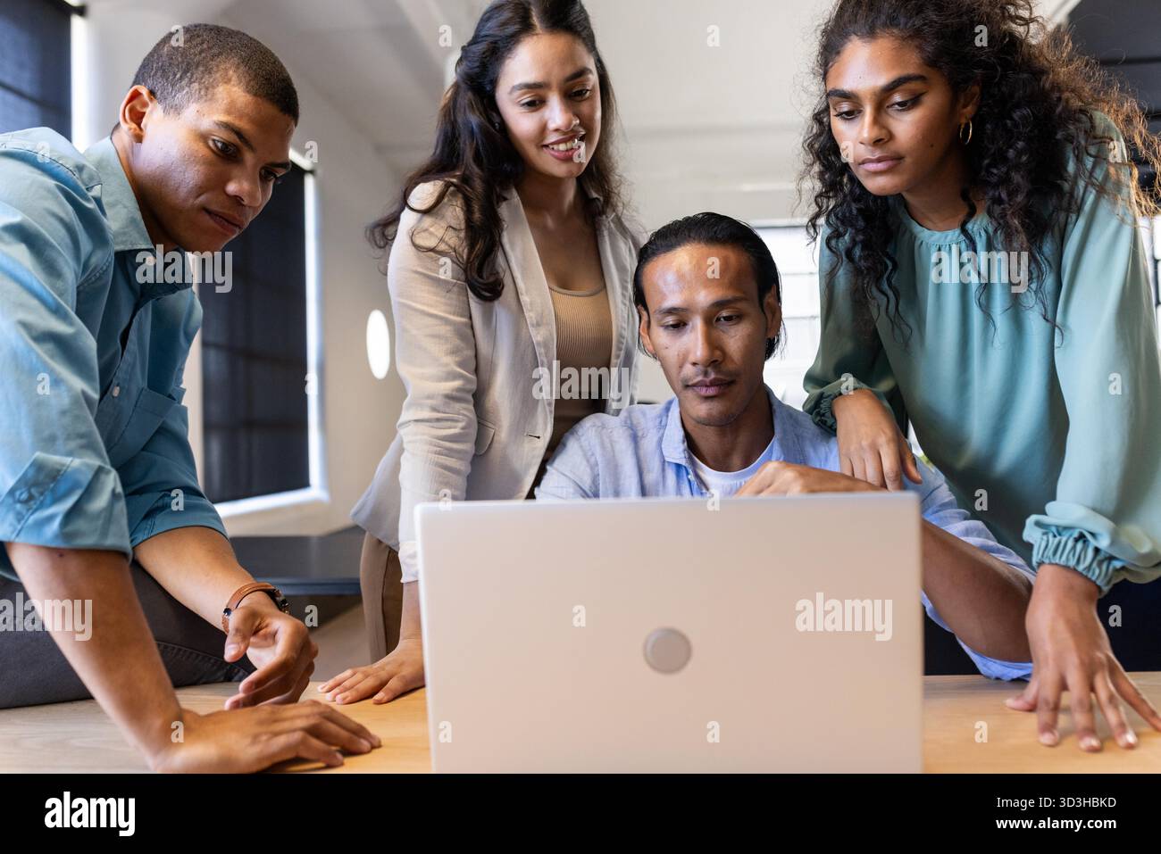 Diverse business team collaborating on laptop project in modern office ...