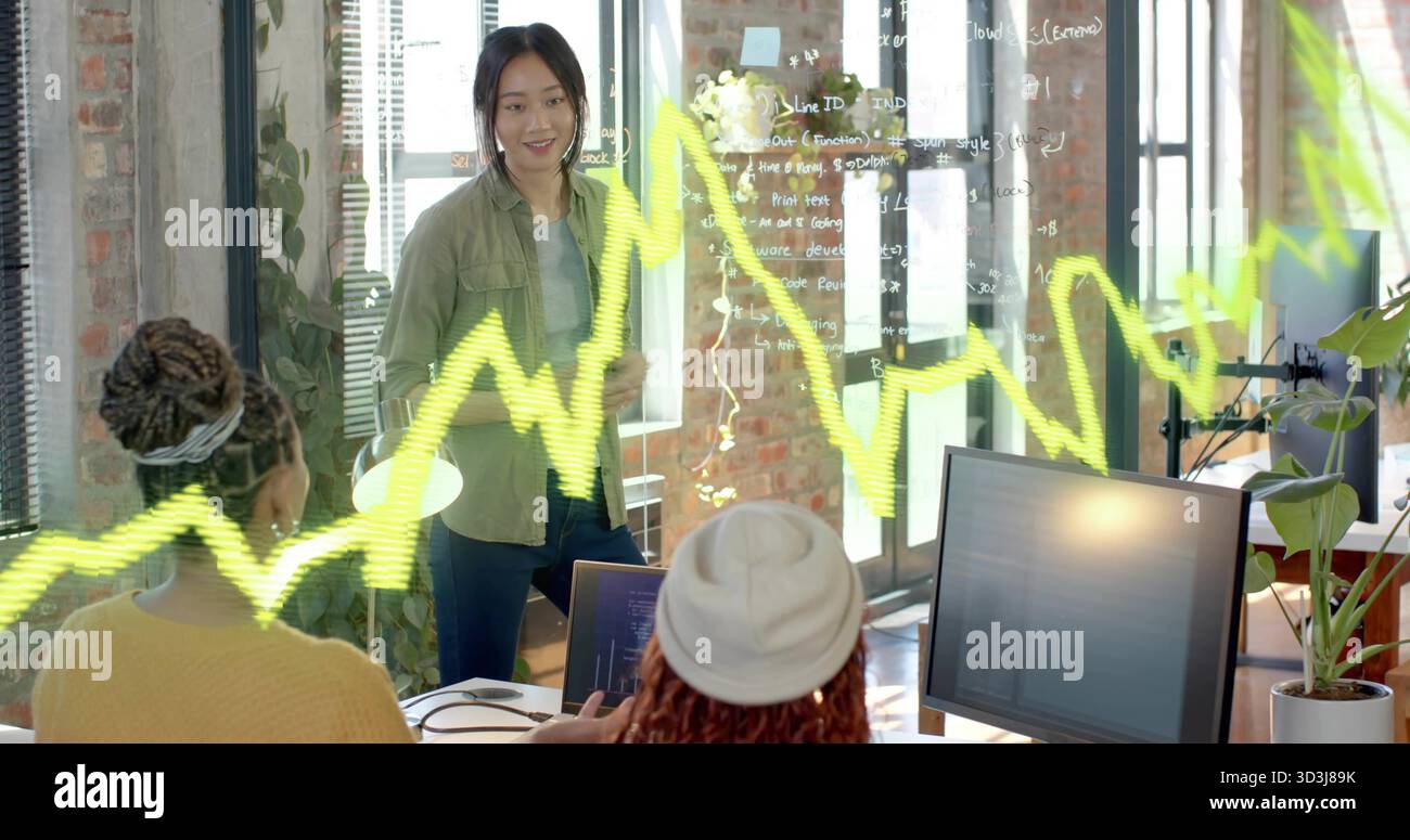 Collaborating women developers writing code on glass panel in loft office, laptops, copy space Stock Photo