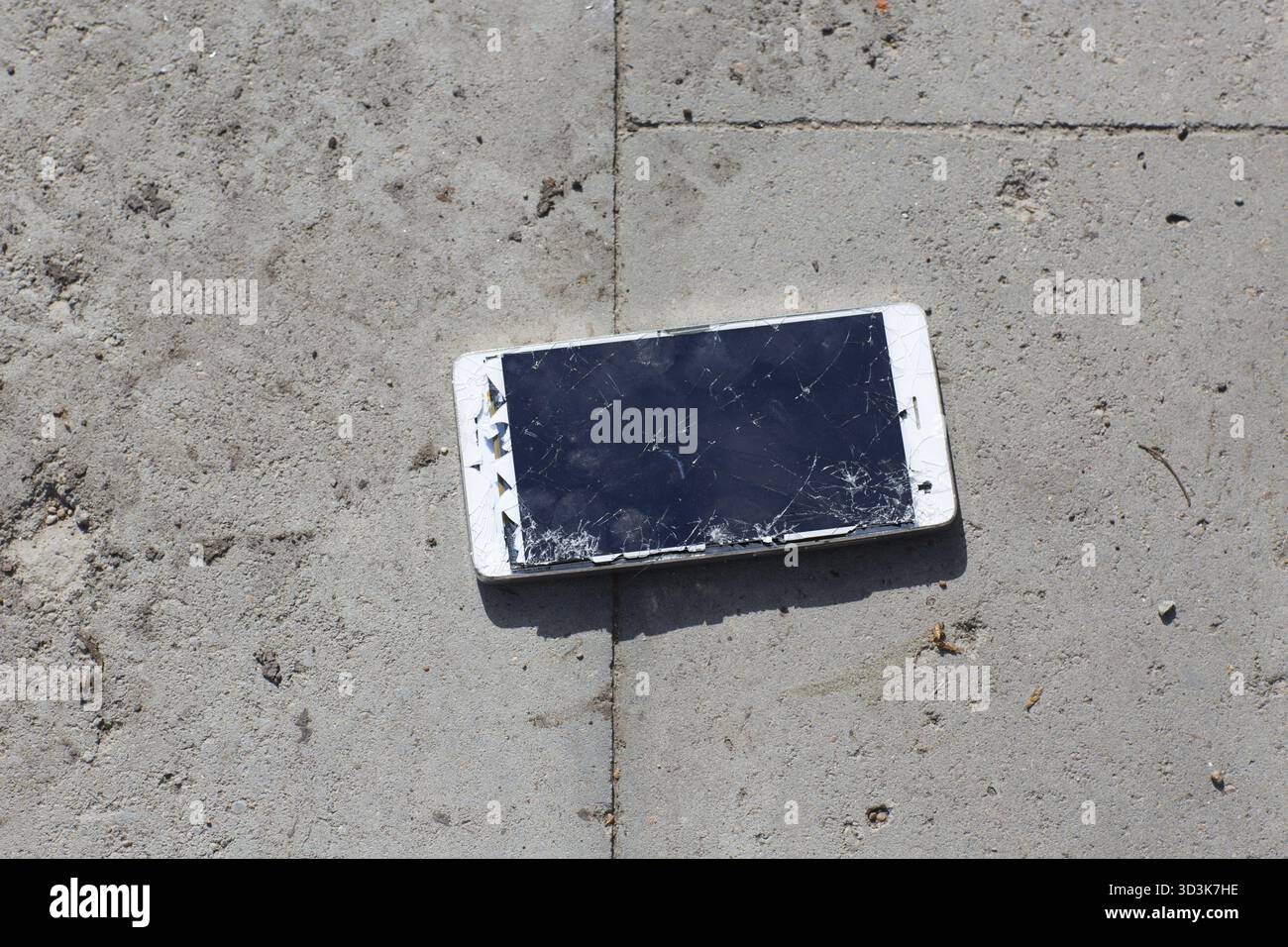 Broken screen mobile phone lies on ground Stock Photo