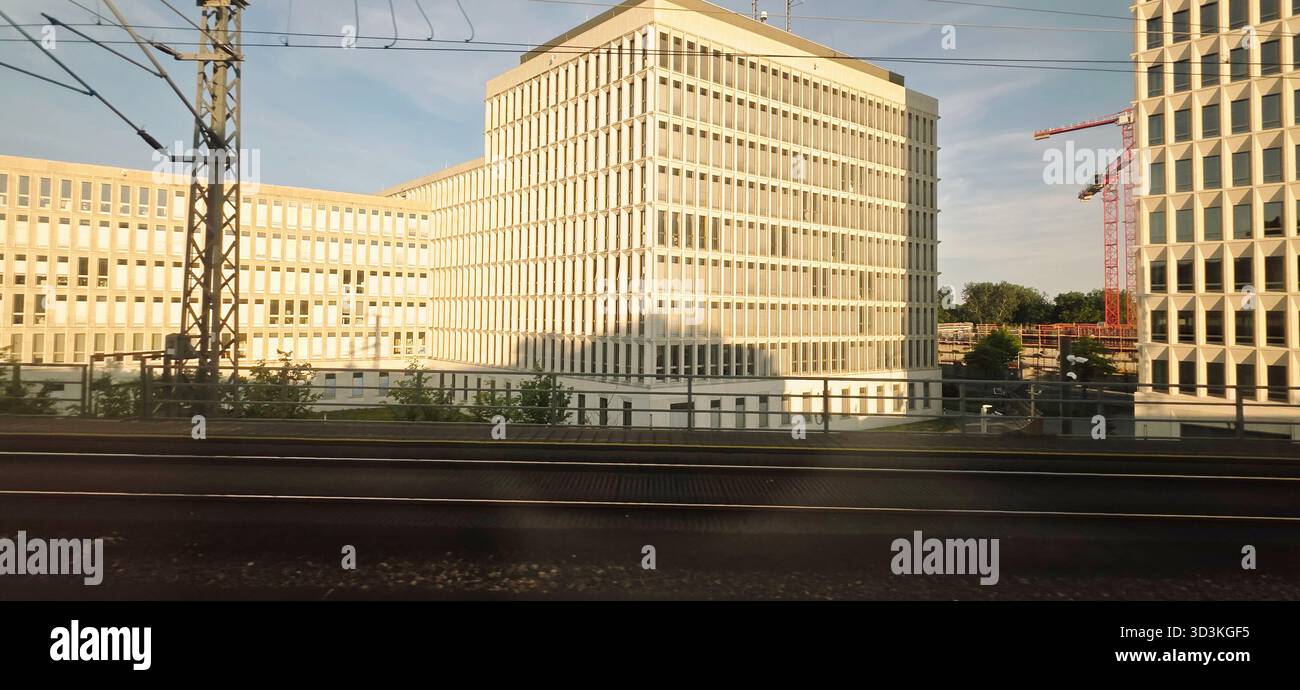Berlin, Germany - June 13, 2025: Modern office structures feature glass facades beside railway tracks in urban setting. - Smartphone Captured Stock Image