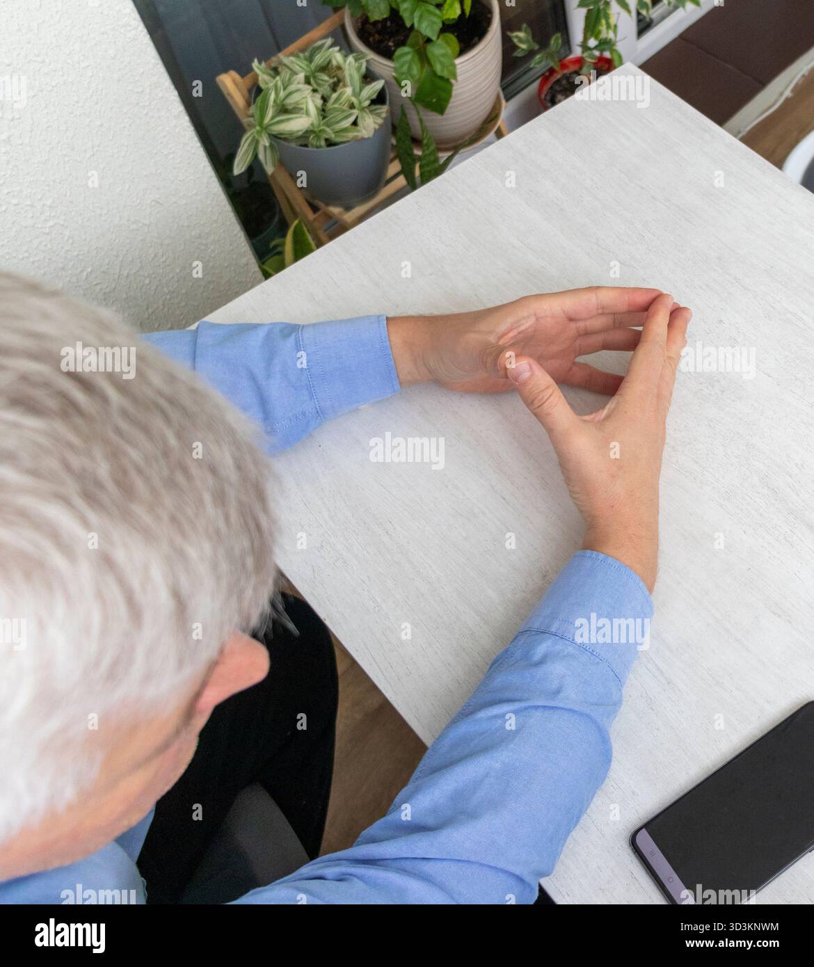 Mid aged man sitting at the table with hands posture in diamond shape Stock Photo