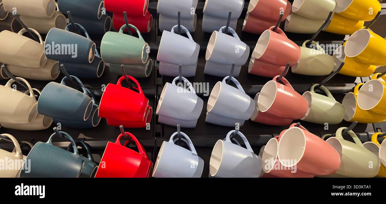 Colorful ceramic mugs are neatly arranged in a modern display, showcasing a variety of vibrant hues and unique designs for visual appeal. - Smartphone Captured Stock Image