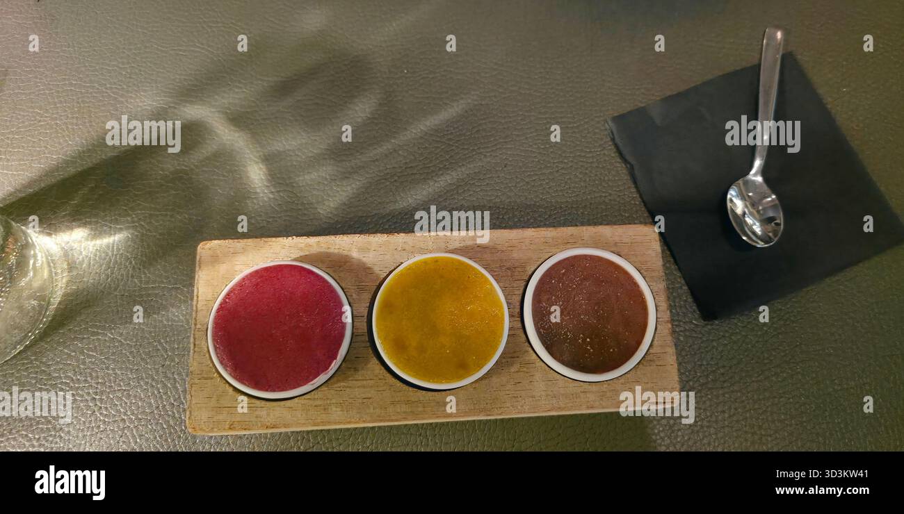 Colorful gourmet sauces are presented in small bowls on a wooden platter, showcasing vibrant textures and culinary artistry. - Smartphone Captured Stock Image