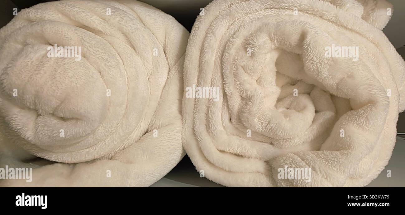 Soft white towels are rolled neatly, creating a cozy atmosphere in a bathroom, inviting relaxation and comfort for users. - Smartphone Captured Stock Image