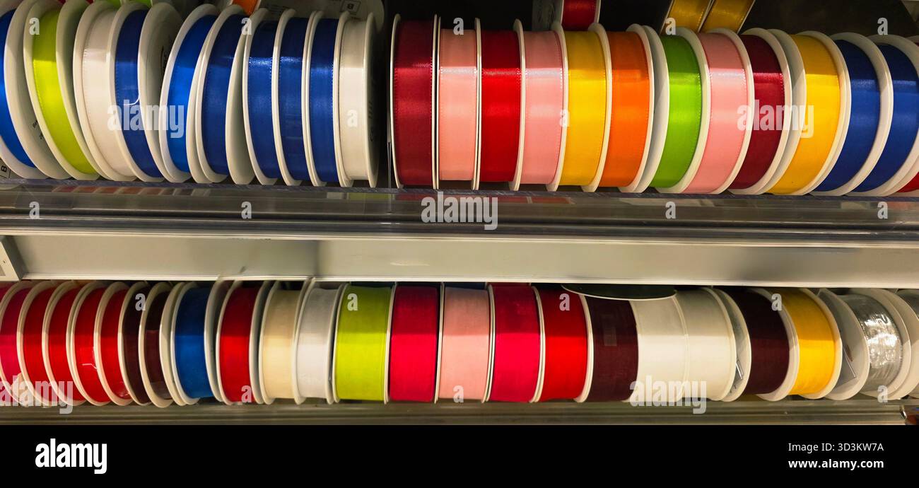 Colorful spools of ribbon are neatly arranged on shelves, showcasing a variety of vibrant colors and textures for crafting projects. - Smartphone Captured Stock Image