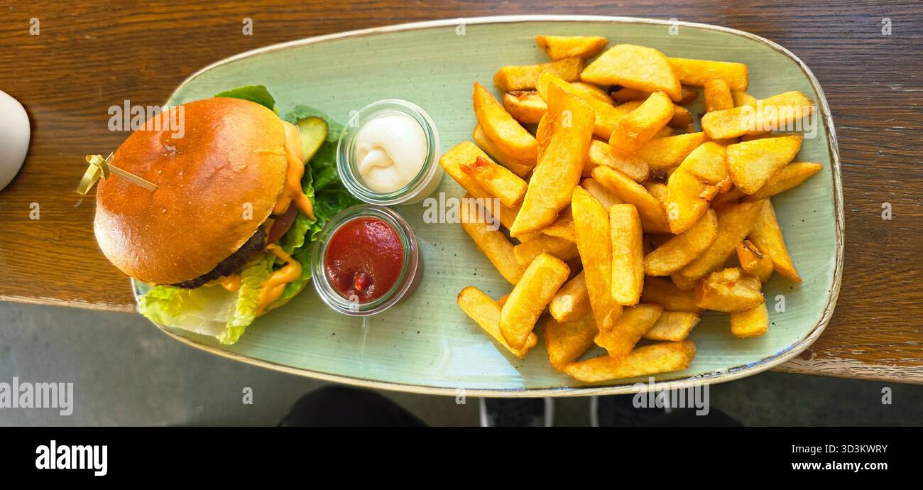A delicious burger accompanied by crispy fries on a green plate, showcasing appetizing textures and vibrant colors for food lovers. - Smartphone Captured Stock Image