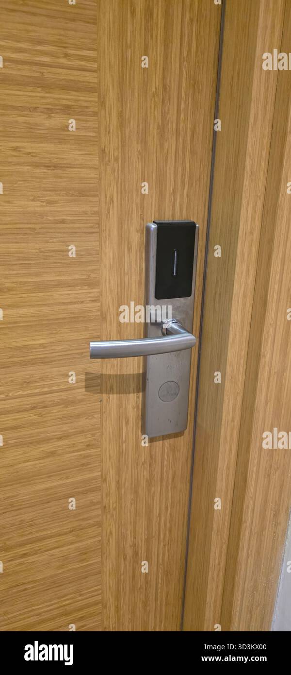 . Modern door handle features an electronic lock on a wooden door, showcasing sleek design and functionality in contemporary architecture - Smartphone Captured Stock Image