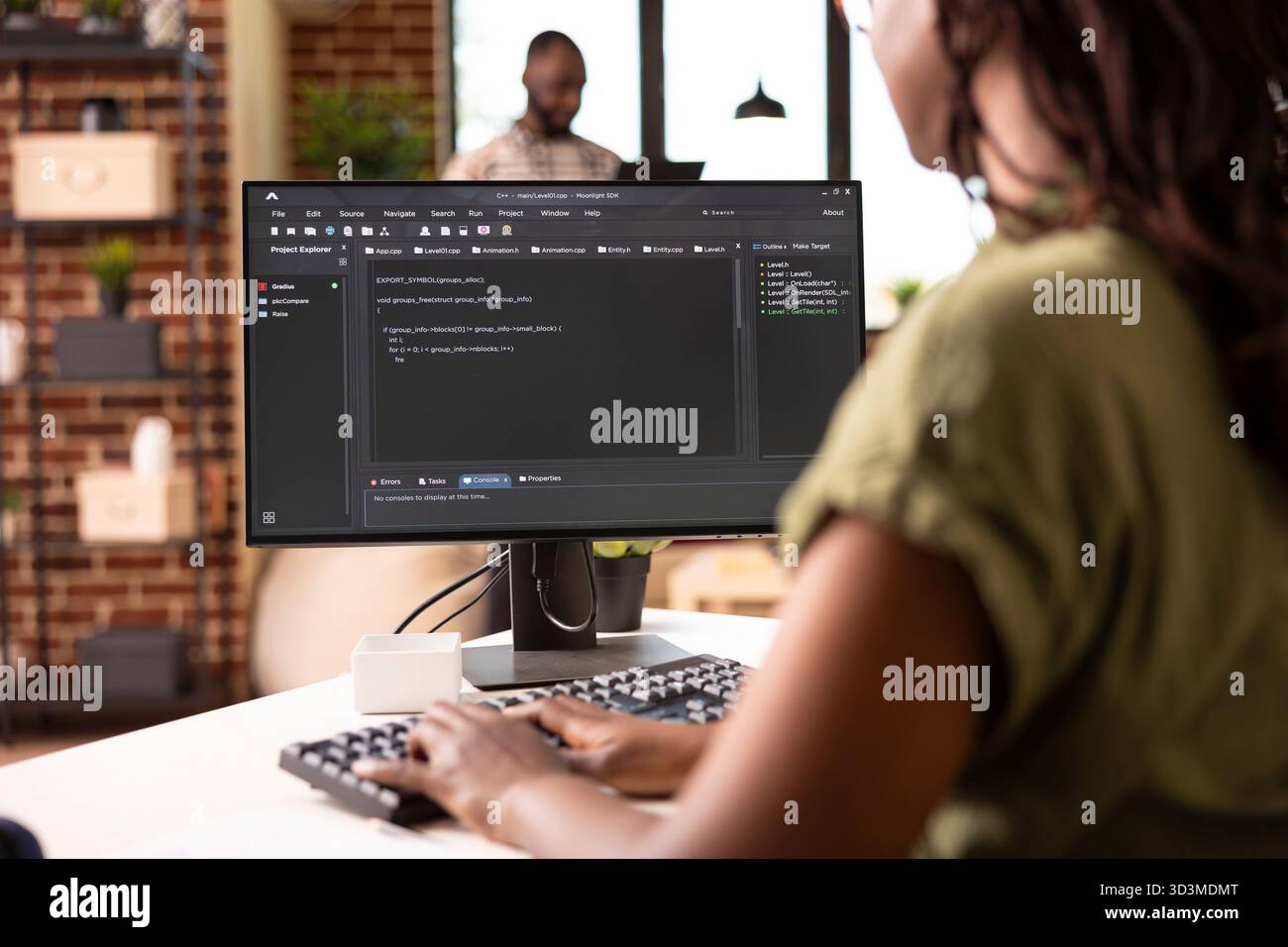 Young female software developer typing code on computer while working on startup project remotely. Black woman using desktop pc and programming new web application from modern apartment. Stock Photo