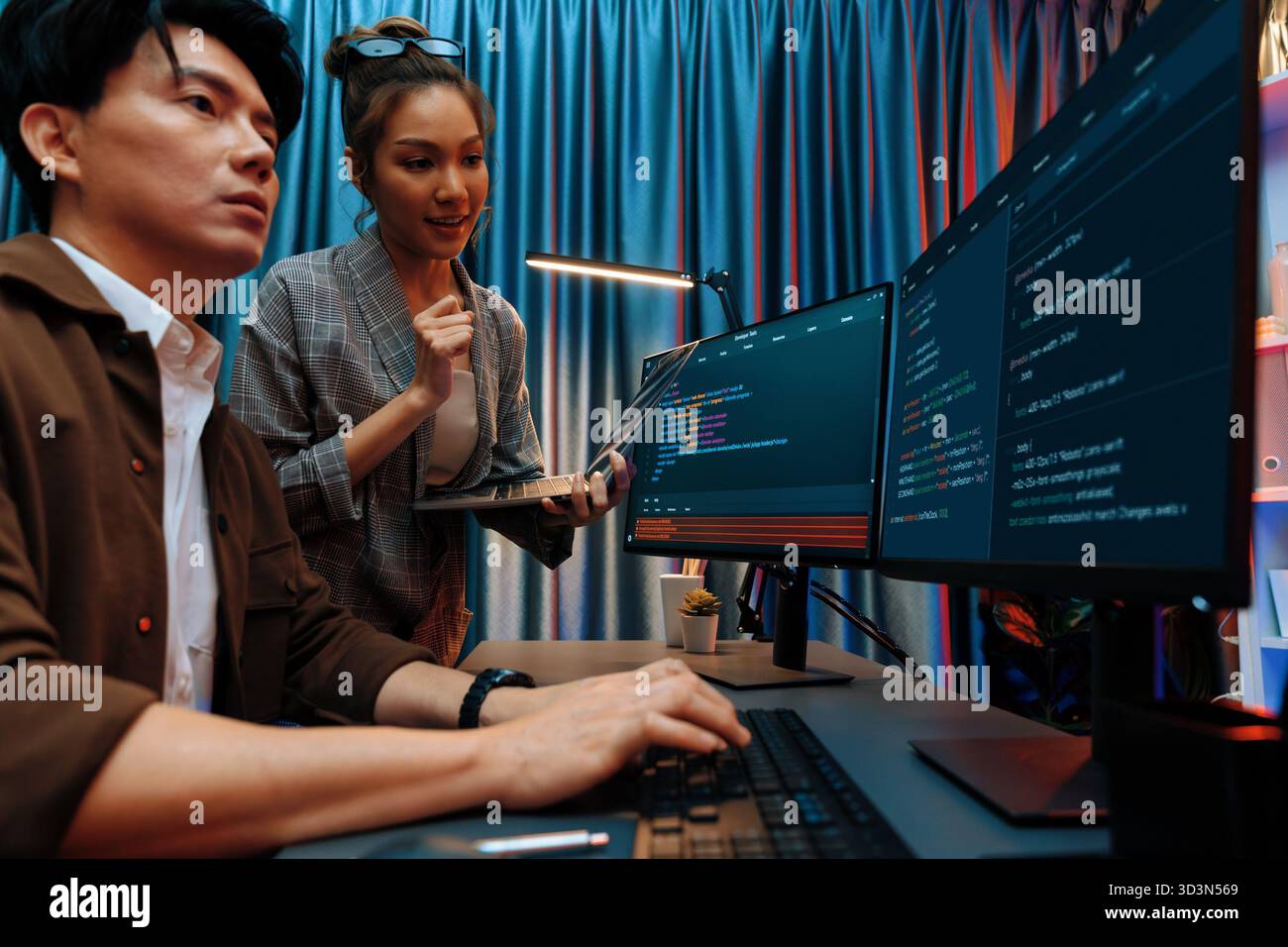Serious of IT developers discussing intelligent website development coder system running data online two screens with laptop showing information Stock Photo