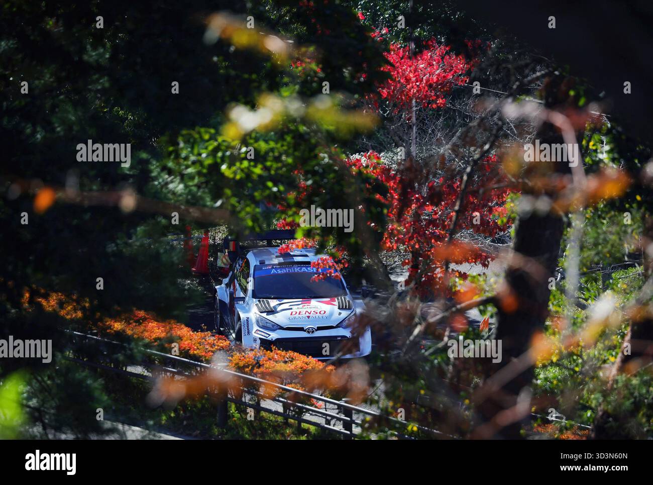 A rally car drives through autumn foliage during a test run at ...