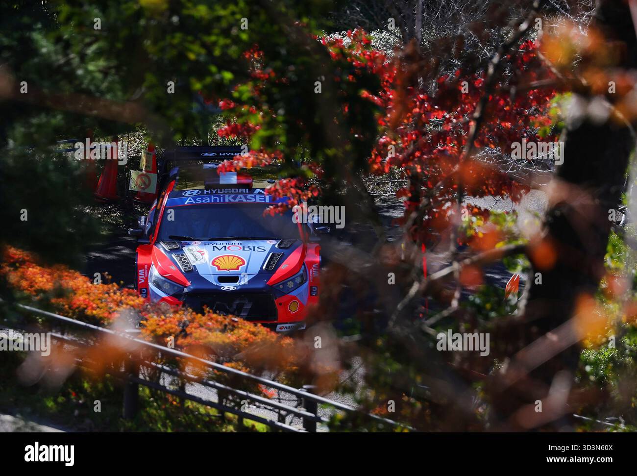 A rally car drives through autumn foliage during a test run at ...