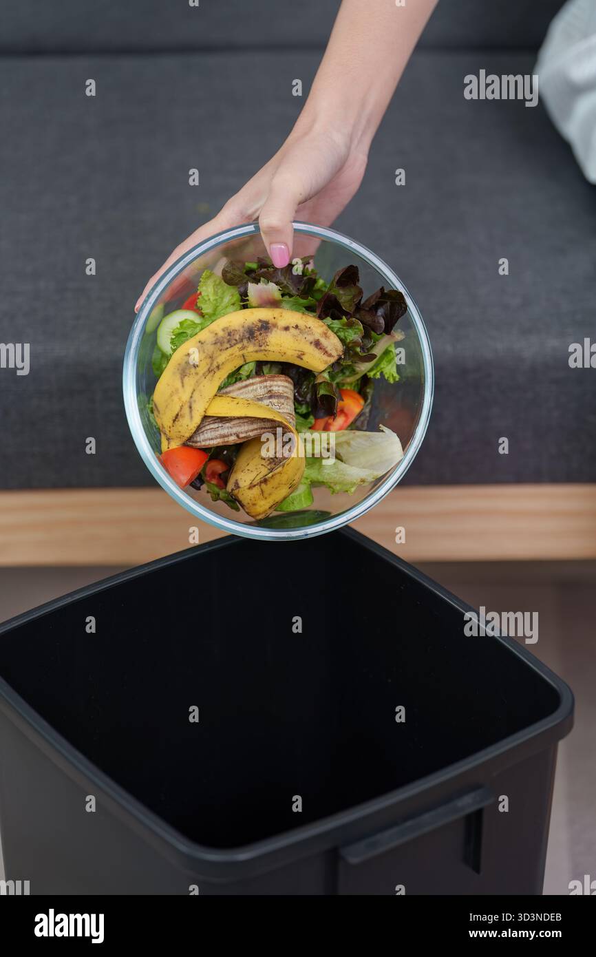 Sustainable living. Woman discarding food waste into trash bin Stock ...