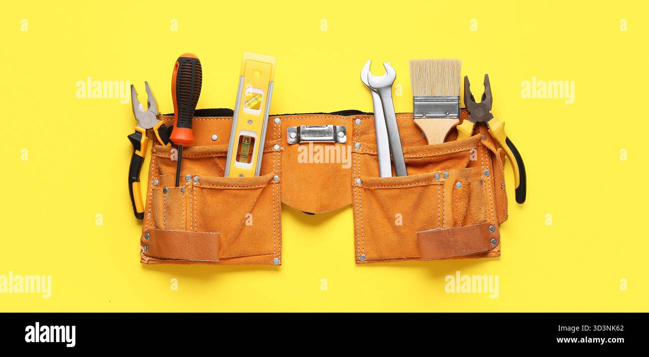 Belt with different construction tools on yellow background, top view Stock Photo