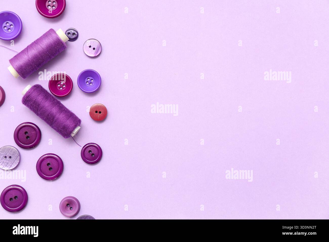 Different buttons and thread spools on lilac background Stock Photo