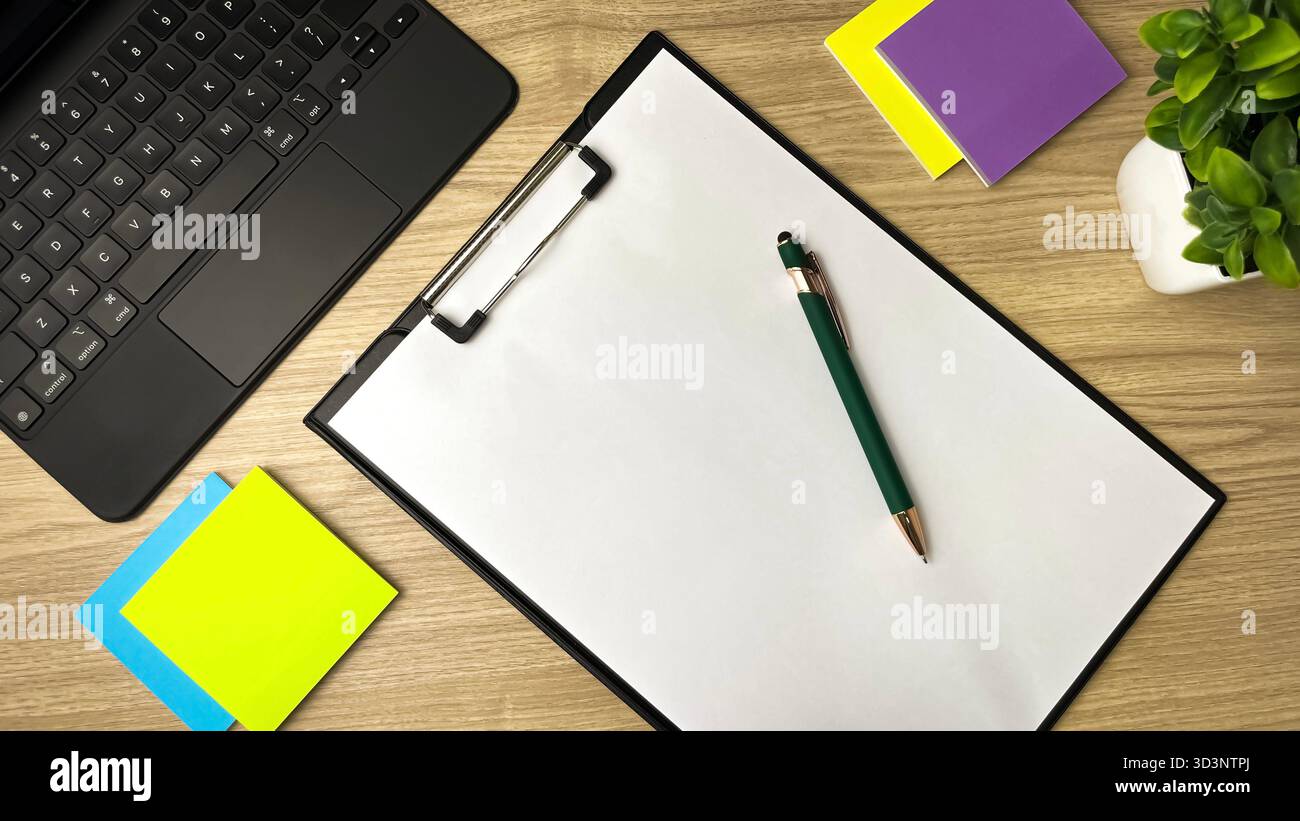 An overhead view of a desk with brightly colored sticky notes, a laptop, and blank notepaper. - Smartphone Captured Stock Image