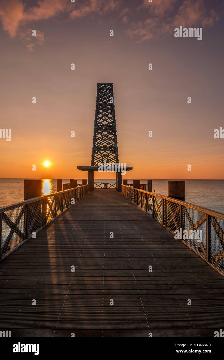 Vertical, symmetrical view of the long wooden pier (le Ponton de Leucate) at golden sunrise, Port Leucate, Aude, France Stock Photo