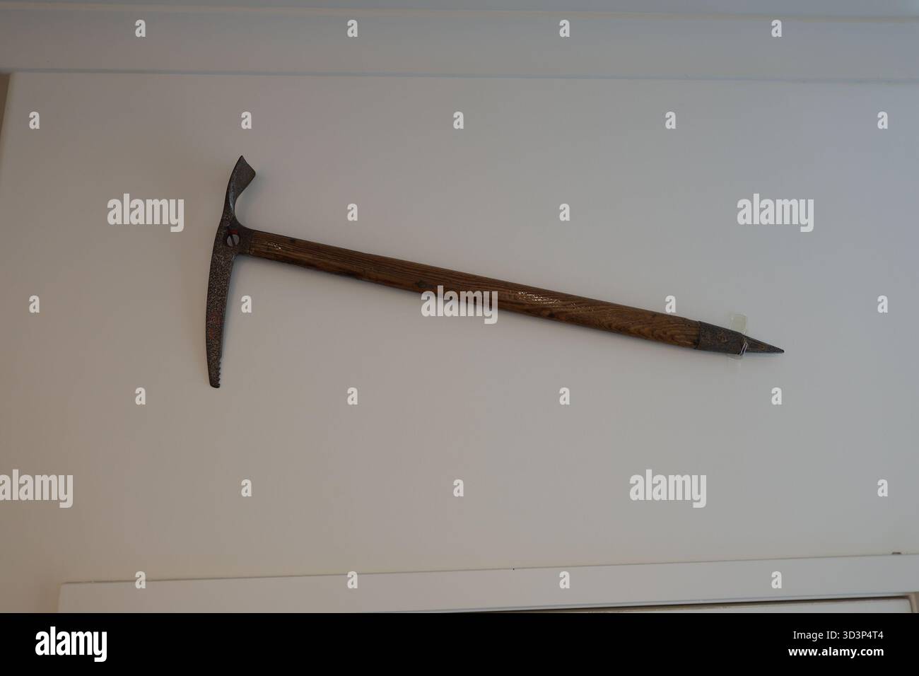 Antique ice axe on white wall Stock Photo