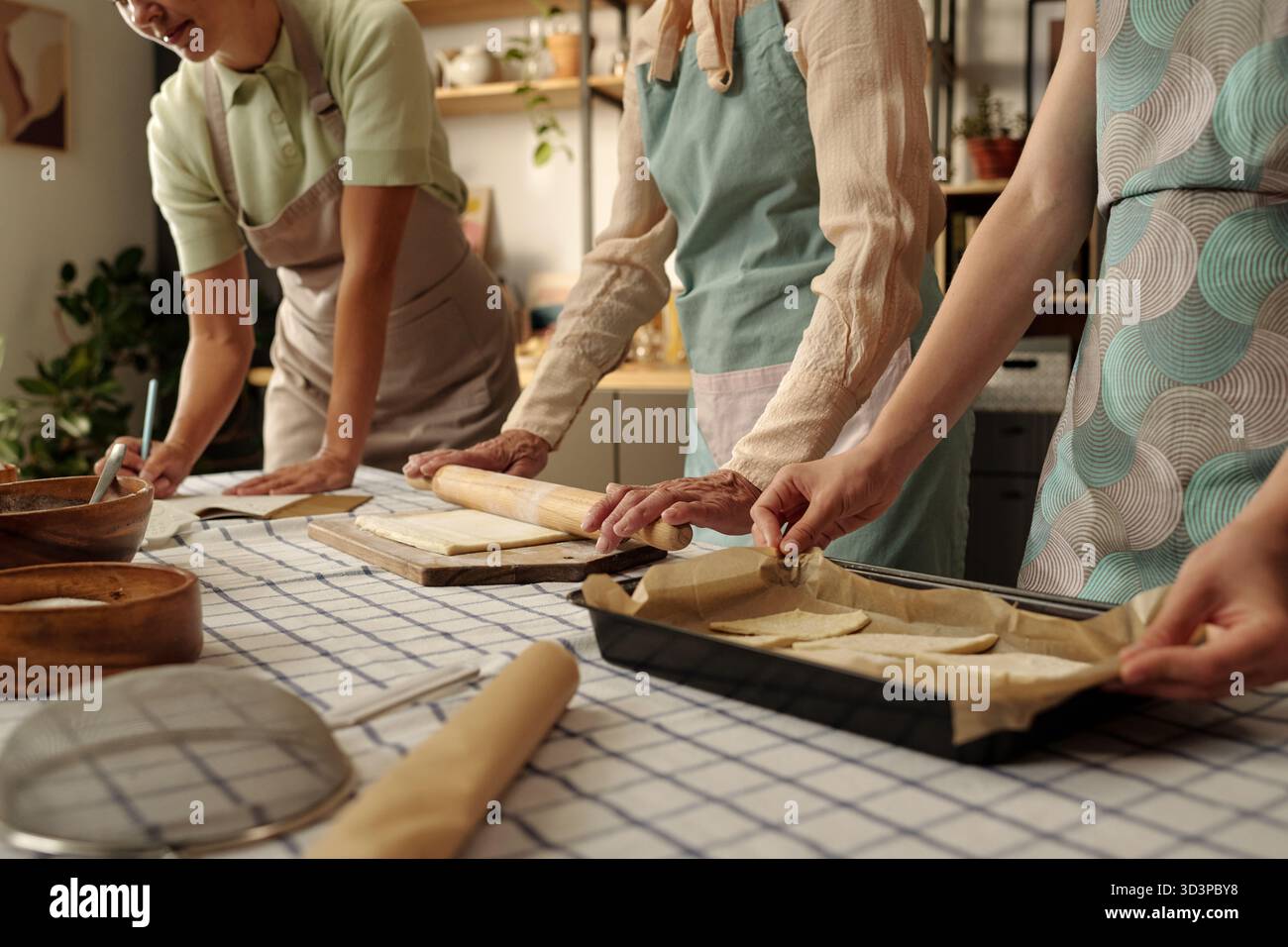Three Caucasian Women Baking Pastries Together in Kitchen Preparing Dough Stock Photo
