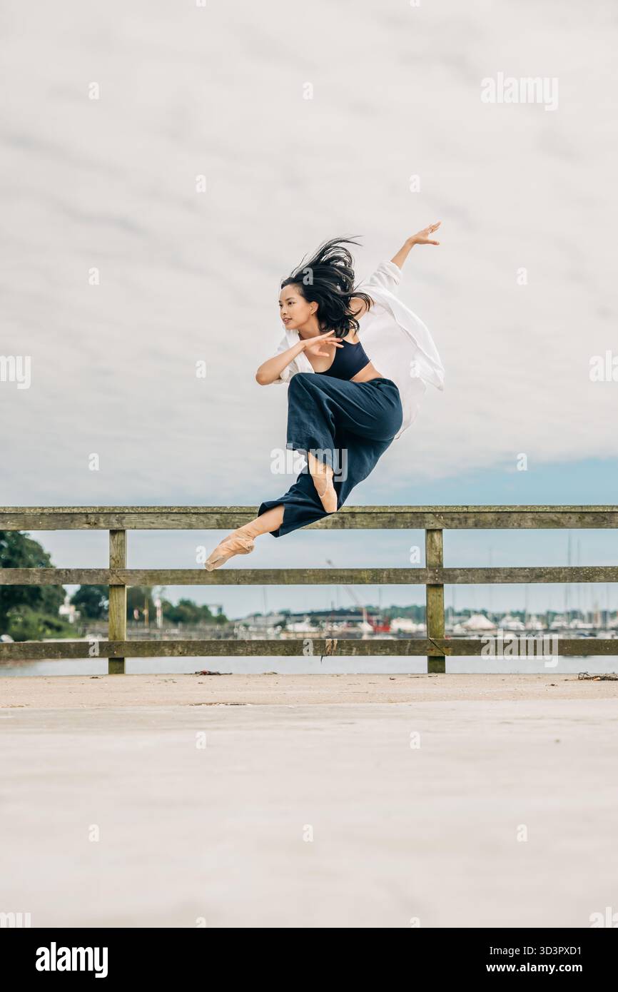 Female dancer performing dynamic jump on pier Stock Photo - Alamy