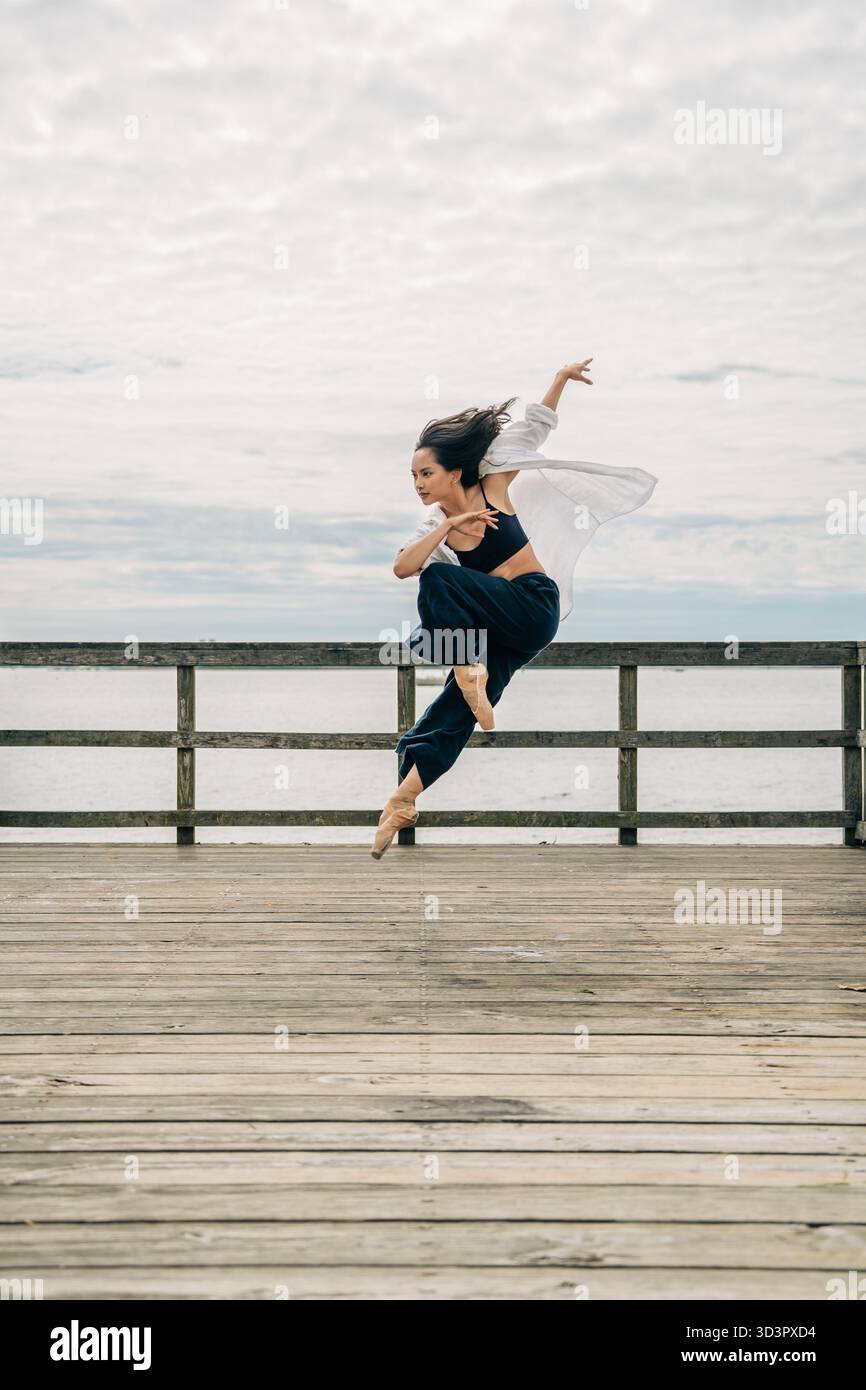 Dancer performing dynamic jump on wooden pier Stock Photo